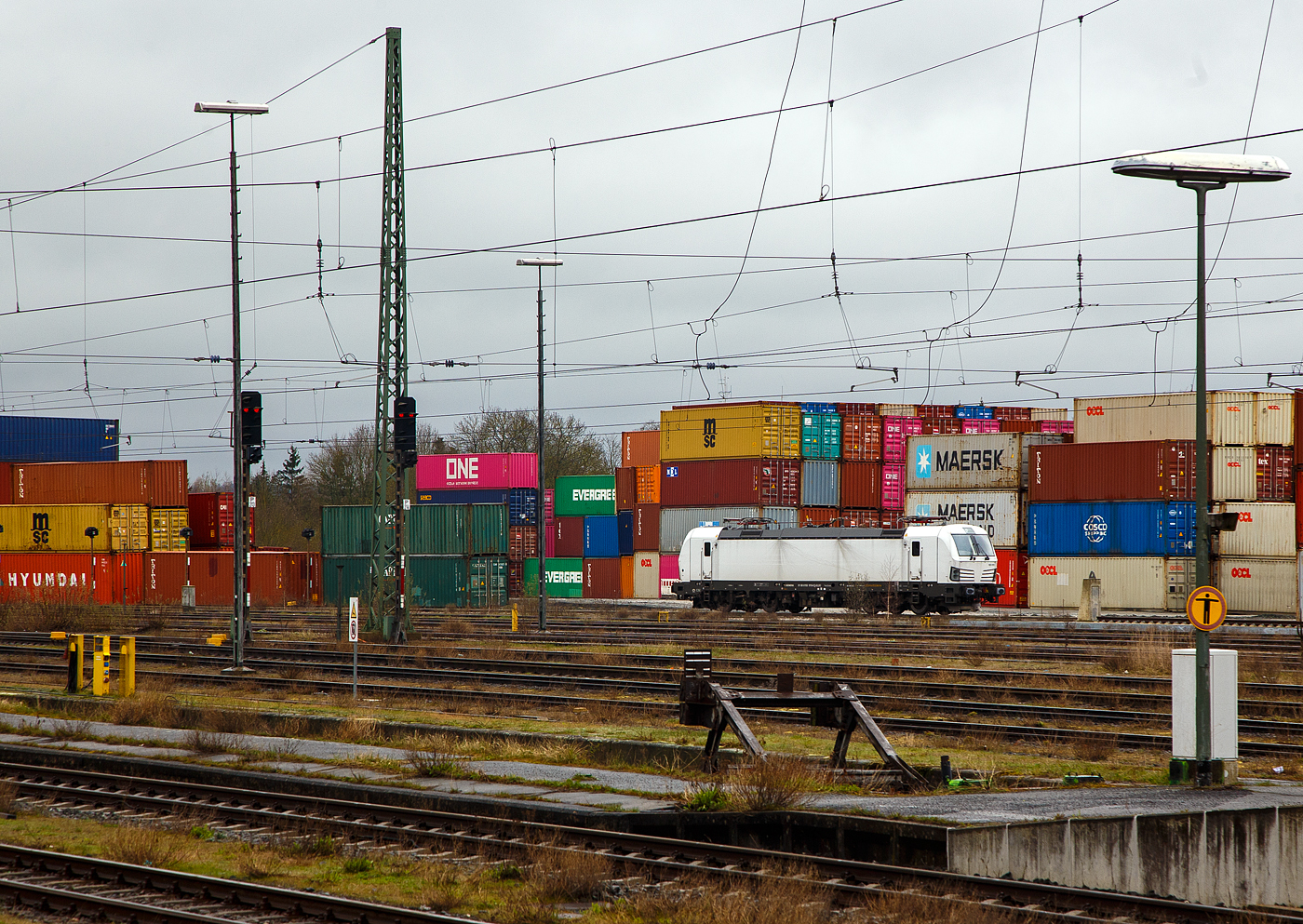 Die weiße SIEMENS Vectron AC DPM 193 919 (91 80 6193 919-8 D-ELOC) steht am 17.04.2023 beim Container Terminal Hof (CTH). Innerhalb des Netzwerks der Contargo Combitrac GmbH stellt das Containerterminal in Hof das „Tor zum Osten“ dar. Dank der günstigen geografischen Lage können von Hof aus sowohl Süd- und Mitteldeutschland, als auch Tschechien und Polen innerhalb kurzer Zeit erreicht werden.

Die SIEMENS Vectron AC DPM mit Diesel Power Modul  bzw. LM (Last Mile Diesel) wurde 2022 von Siemens Mobilitiy in München-Allach unter der Fabriknummer 22968 gebaut. Diese Vectron Lokomotive ist als AC DPM – Lokomotive (Wechselstrom-Variante mit Dieselmodul für Rangieren ohne Fahrdraht) mit 6.400 kW konzipiert und zugelassen für Deutschland, Österreich Ungarn und Rumänien (D/A/H/RO), im Dieselbetrieb beträgt die Leistung lediglich 180 kW (160 kW am Rad).
