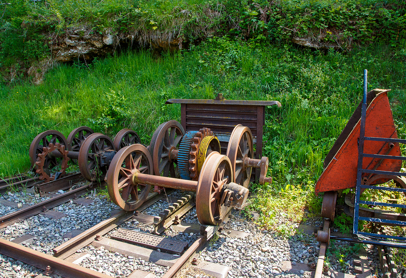 Drei unterschiedliche Zahnradsysteme gesehen am 27.05.2023 im Museumsareal in Chaulin der Museumsbahn Blonay–Chamby.

Links Leiterzahnstangen und Zahnrad nach dem System Riggenbach. Die Zahnstange von Niklaus Riggenbach wurde 1863 in Frankreich patentiert. Zwischen zwei U-f�rmigen Profilen sind die Z�hne als Sprossen eingesetzt. Urspr�nglich waren sie genietet, heute werden sie geschwei�t. Diese Bauart zeichnet sich aus durch trapezf�rmige Z�hne, was Evolventenverzahnung und damit eine konstante Kraft�bertragung erm�glicht. Die Riggenbach-Zahnstange ist wegen ihrer massiven Konstruktionsweise robust und l�sst sich mit einfachen Mitteln fertigen. Sie erreichte die zweitgr��te Verbreitung aller Systeme.

In der Mitte Zahnschienen und Zahnrad (auf einer Achse) nach dem System Strub. Die Strub’sche Breitfu�schiene mit Evolventenverzahnung ist das j�ngste der drei Systeme mit nach oben zeigenden Z�hnen (Riggenbach, Strub und Abt). Die erste Anwendung war die Jungfraubahn im Berner Oberland. Die seitdem gebauten Zahnradstrecken verwendeten vorwiegend nur noch diese Zahnstange. Ihre Verbreitung blieb aber gering, weil danach kaum noch neue Zahnradstrecken gebaut wurden.

Die Z�hne sind in eine der Keilkopfschiene �hnlichen Schiene eingefr�st. Die Herstellung der Strub-Zahnstangen ist teuer, ihre Verlegung aber einfach. Sie werden wie Fahrschienen nach der Oberbauform K mit Rippenplatten auf den Schwellen befestigt (gleiches Befestigungsmaterial f�r Fahr- und Zahnschienen), sie k�nnen l�ckenlos verschwei�t werden und im Unterhalt sind sie anspruchslos. 

Auf dem Meterspurnetz der Appenzeller Bahnen wurden Zahnstangen vom System Strub mit den gleichen Zahnr�dern wie die Riggenbachsche Leiterzahnstangen befahren, weil die Teilung und H�henlage beider Zahnstangen identisch war.

Und Rechts eine zweilamellige Lamellenzahnstangen nach dem System Abt. Als Weiterentwicklung zum System Riggenbach wurden zwei oder drei mit nach oben zeigenden Z�hnen versehene Zahnstangen („Lamellen“) nebeneinander eingebaut. Die relativ schmalen Stangen sind zur Anpassung an beliebige Bogenradien gen�gend biegbar. Durch die Vervielf�ltigung der Stangen blieb die Kontaktfl�che zwischen Zahnrad und Zahnstangen ausreichend gro�. Die Breite der Lamellen h�ngt vom gr��ten auftretenden Zahndruck ab.Als Einziger verwendete Abt eine Zahnteilung von 120 mm anstatt der �blichen 100 mm. Diese Mehrlamellenbauart erreichte weltweit die gr��te Verbreitung. 
