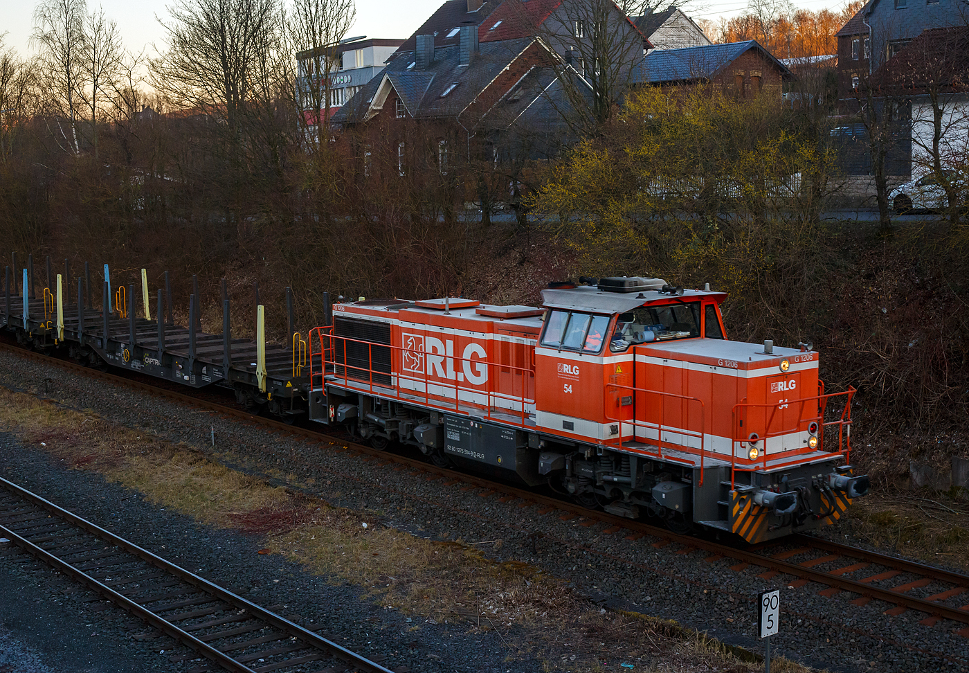 Eigentlich wollten wir nur noch im St�dtchen was Einkaufen, aber dann sah ich das Signal Hp 2….
Die RLG 54 / 175 504-9 (92 80 1275 504-9 D-RLG) eine MaK G 1206 der RLG - Regionalverkehr Ruhr-Lippe GmbH (Soest), vermietet ans Schwesterunternehmen WLE - Westf�lische Landes-Eisenbahn GmbH, kommt am 18. M�rz 2025 auf ihrer Heimreise mit einem leeren G�terzug (Schwerlastwagen) von der Mannesmann Precision Tubes GmbH in Burbach-Holzhausen �ber die Hellertalbahn durch Herdorf.

Die G 1206 wurde 2008 von Vossloh in Kiel unter der Fabriknummer 5001638 gebaut. Sie war die erste wieder mit einen MTU gebaute G 1206. So hat sie einen wassergek�hlten V12-Zylinder-Dieselmotor mit Abgasturbolader und Ladeluftk�hlung vom Typ MTU mit einer Leistung von 1.500 kW (bei 1.800 U/min).

TECHNISCHE DATEN der G 1206:
Spurweite: 1.435 mm
Antriebart:  dieselhydraulisch
Achsfolge: B'B' 
L�nge �ber Puffer: 14.700 mm
Drehzapfenabstand: 7.200 mm
Achsabstand im Drehgestell: 2.400 mm
gr��te Breite: 3.080 mm
H�he �ber Schienenoberkante: 4.220 mm
Raddurchmesser neu: 1.000 mm
Motor: MTU 12 Zylinder 4-Takt Dieselmotor mit Abgasturbolader und Ladeluftk�hlung vom Typ 12V 4000 R41
Leistung: 1.500 kW bei1.800 U/min
Str�mungsgetriebe: Voith L 5r4 zseU2
Anfahrzugkraft: 267 kN
H�chstgeschwindigkeit: 100 km/h
kleinster befahrbarer Gleisbogen:	60 m
Dienstgewicht: 88 t
Kraftstoffvorrat: 3.150 l