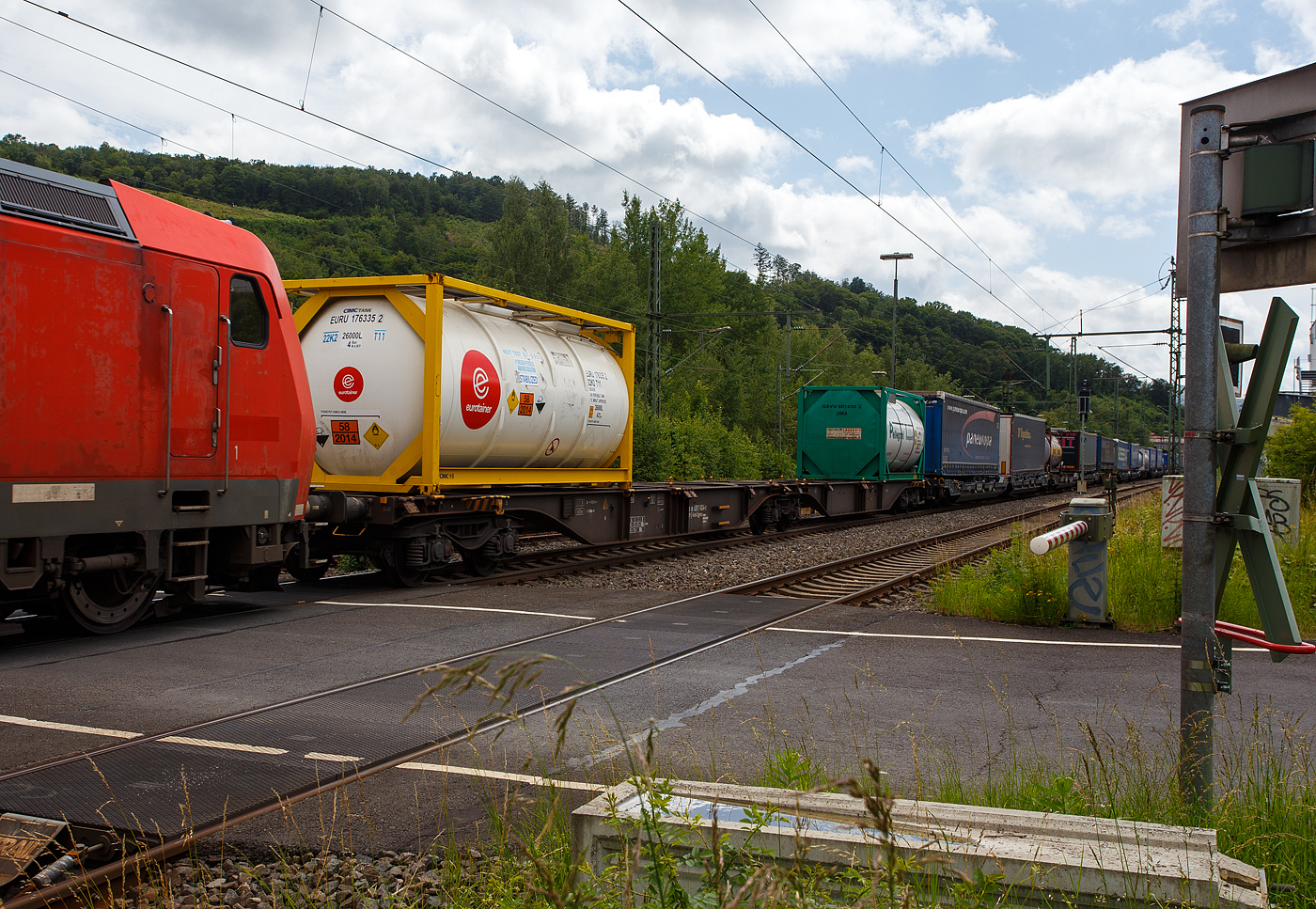 Ein langer sechsachsige Drehgestell-Gelenk-Containertragwagen-Einheit (6- achsiger Containertragwagen-Einheit), 33 80 496 1 024-3 D-Kombi, der Gattung Sggmrss (104‘), der Kombiverkehr GmbH & Co KG (Frankfurt am Main), hier beladen mit 2 Tank-Containern, am 21 Juni 2024 im Zugverband (hinter der DB 185 154-2) bei der Zugdurchfahrt in Niederschelden (Siegstrecke). 

Der Wagen wurde 2002 vom polnischen Hersteller Europejskie Konsorcjum Kolejowe WAGON Sp. z o.o. (heute Polski Tabor Szynowy – Wagon Sp. z o.o.) in Ostrów Wielkopolski (PL) gebaut. Er hat die EBA-Nr.r 01 L16 A025.

Jeder Wagen kann mit 4 Wechselbehältern / Containern (7,15 m, 7,45 m und 7,82 m), beladen werden, mit einem Gesamtladegewicht von 105 t. Dadurch wird in der Zugkomposition Ladelänge und Gewicht eingespart.

TECHNISCHE DATEN (laut Anschriften):
Spurweite: 1.435 mm
Anzahl der Achsen: 6 in drei Drehgestellen
Länge über Puffer: 33.480 mm
Drehzapfenabstände: 2 x 13.970 mm
Eigengewicht: 29.740 kg
Max. Zuladung bei Lastgrenze S: 104,0 t (ab Streckenklasse D)
Max. Zuladung bei Lastgrenze SS: 90,0 t (ab Streckenklasse C)
Max. Geschwindigkeit: 100 km/h (Lastgrenze SS oder leer 120 km/h)
Kleinster bef. Gleisbogenradius: R 75 m (Einzelwagen) / R 150 (Zugverband)
Bremse: 2 x MH-GP-A (K)
Bremssohle: Jurid 816M
Verwendungsfähigkeit: RIV

Die Kombiverkehr GmbH & Co KG ist ein logistisches Dienstleistungsunternehmen und ein Eisenbahnverkehrsunternehmen mit Sitz in Frankfurt am Main (Deutschland). Gegründet wurde die Gesellschaft am 11. Februar 1969 durch 56 Straßentransporteure und Kraftwagenspediteure. Bis zur Beteiligung der DB Mobility Logistics AG mit 50 % im Jahr 2002 hielten die Spediteure 100 % der Kommanditanteile. Im März 2023 waren 225 nationale und internationale Speditionen sowie die DB Cargo Kommanditisten.

Von der Kombiverkehr GmbH & Co KG wird ein Netz für den Kombinierten Verkehr Schiene-Straße in Europa entwickelt, organisiert und vermarktet. Als ergänzende Leistungen werden u. a. der Aufbau und Betrieb von Umschlaganlagen und die Entwicklung und Unterhaltung von Spezialwaggons erbracht. Kombiverkehr ist seit November 1999 als öffentliches Eisenbahnverkehrsunternehmen zugelassen und kann Trassenleistungen direkt bei den Netzbetreibern einkaufen und Eigentraktionen durchführen. Kombiverkehr ist auch an vielen Terminals beteiligt.

