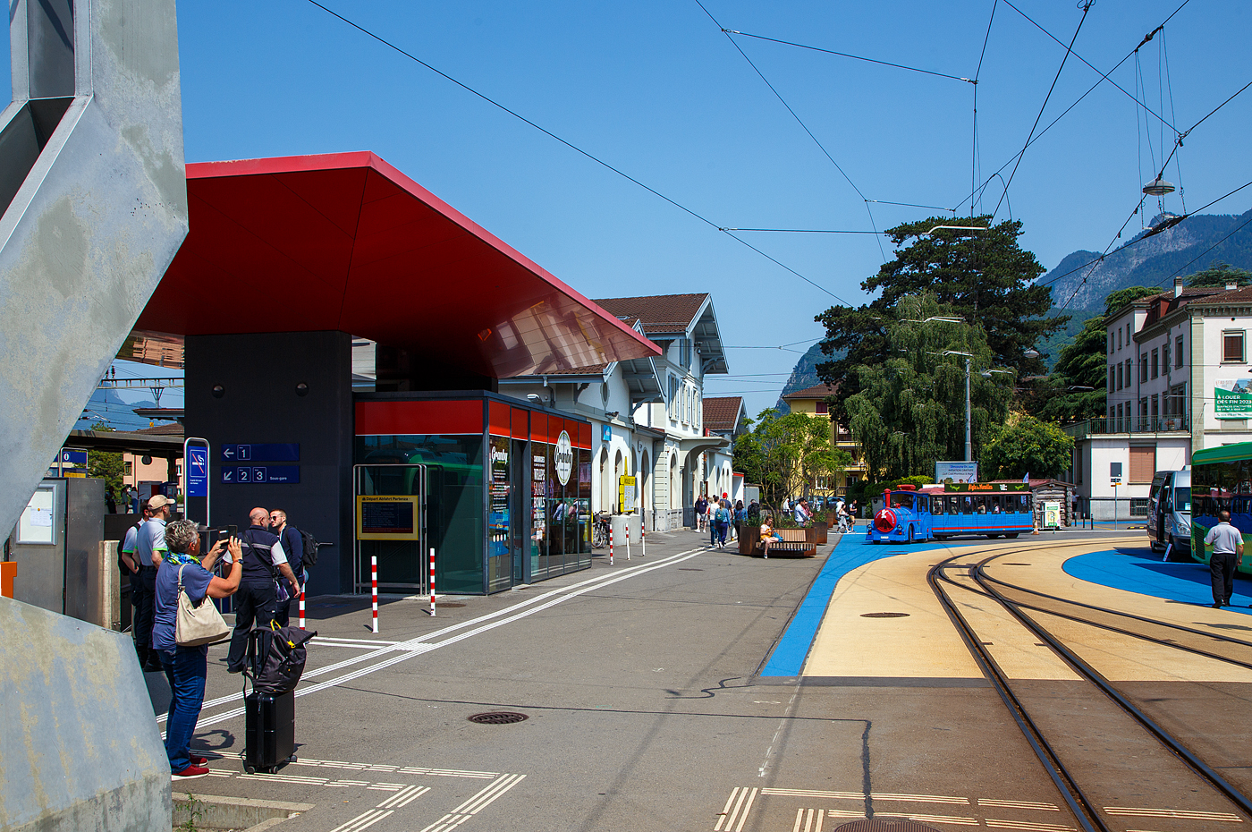 Ein Petit Train (ein Muson River 1894 vom italienischen Hersteller DOTTO TRAINS mit einem Anhänger) erreicht am 28 Mai 2023 den Bahnhof Aigle. Er ist aber wohl keine Konkurrenz zur AL - Aigle–Leysin-Bahn, deren Meterspur Gleise nach Leysin-Grand-Hôtel hier rechts liegen.

Links das Empfangsgebäude vom SBB Bahnhof.
Der Bahnhof Aigle wurde am 10. Juni 1858 von der Compagnie de l’Ouest Suisse zusammen mit dem Abschnitt Villeneuve–Bex der normalspurigen Strecke Lausanne–Les Paluds, Teil der heutigen Simplonstrecke der Schweizerischen Bundesbahnen, eröffnet.

Von Aigle aus wurden die Meterspur-Strecken nach Leysin im Jahr 1900, nach Monthey 1907 und nach Sépey 1913 eröffnet, die heute von den Transports Publics du Chablais betrieben werden.
