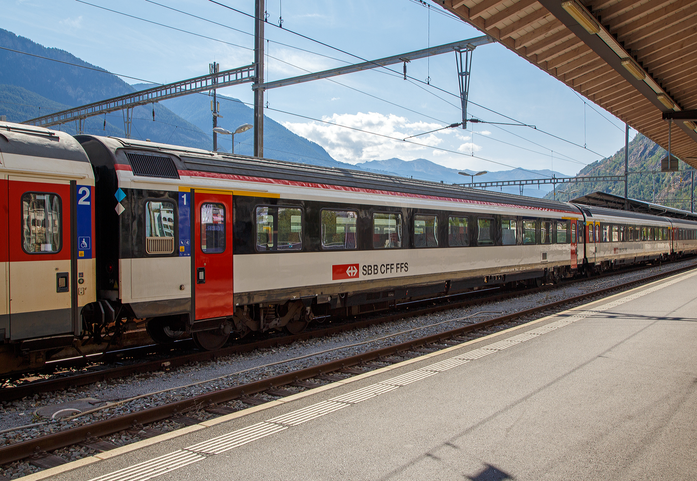 Frisch revidierter SBB IC-Reisezugwagen der ersten Wagenklasse (Einheitswagen IV) A 50 85 10-75 173-0 CH-SBB eingereiht in einen IR 90 nach Genève-Aéroport (Genf Flughafen) am 07 September 2021 im Bahnhof Brig. Die Revision R2 war am 23.04.2021.

Nach den eher durchwachsenen Erfahrungen mit den Einheitswagen III entwickelte die Waggon-Industrie zusammen mit den SBB die neuen Einheitswagen IV. Von den ursprünglich grün-steingrau lackierten Wagen wurden von 1981 bis 1992 über 500 Stück gebaut.  

Zwischen 1995 und 1998 wurden 300 Einheitswagen IV pendelzugfähig gemacht. Und dazu wurden 90 neue IC Steuerwagen Bt beschafft, die den Wagen anglichen waren. Ab 2000 wurden die Wagen teilweise auf eine Höchstgeschwindigkeit von 200 km/h (vorher 160 km/h) ertüchtigt, aber nicht dieser. Die Toiletten erhielten eine Vakuumeinrichtung, da offene Systeme (Fallrohrtoiletten) auf der NBS behördlich verboten sind. Nach dem Umbau in Pendelzugwagen haben die Wagen die Bezeichnung -75 statt -73. Für 200 km/h geeignete Pendelzug-Wagen erhalten die Bezeichnung -95. 

Seit 2021 erhalten die EW IV ein neues Farbkleid, das am ehesten durch die Türen in RAL 3000 (Feuerrot) auffällt. Damit werden Vorschriften des Behindertengleichstellungsgesetzes betreffend Sichtbarkeit und Kontrast der Türbereiche umgesetzt. Außerdem wird die seitliche Unterbodenverkleidung, die bisher grau war, sowie auch das Fensterband an den Wagenenden (vorher rot) nun neu schwarz lackiert, um damit dem Design der Neubaufahrzeuge zu entsprechen. Zudem ziert eine neue, durchgehende rote Längslinie den Übergang von der Seitenwand zum Dach. Die Unterschiede der Farbkleider sind hier im Bild gut zusehen 

Gleichzeitig, aber unabhängig vom oben genannten Neulackierungs-Programm werden auch die Türen umgebaut. Diese werden vom alten pneumatischen Antrieb auf elektrischen Antrieb umgebaut.

TECHNISCHE DATEN:
Spurweite: 1.435 mm (Normalspur)
Länge über Puffer: 26.400mm 
Drehzapfenabstand: 18.600 mm
Höchstgeschwindigkeit: 160 km/h
Eigengewicht: 42 t
Bremse: O-PR+Mg (D)
Sitzplätze: 60 in der 1. Klasse
Toilette: 1 Toiletten (geschlossenes Systeme/ Vakuumsystem)
Zulassung: NBS
