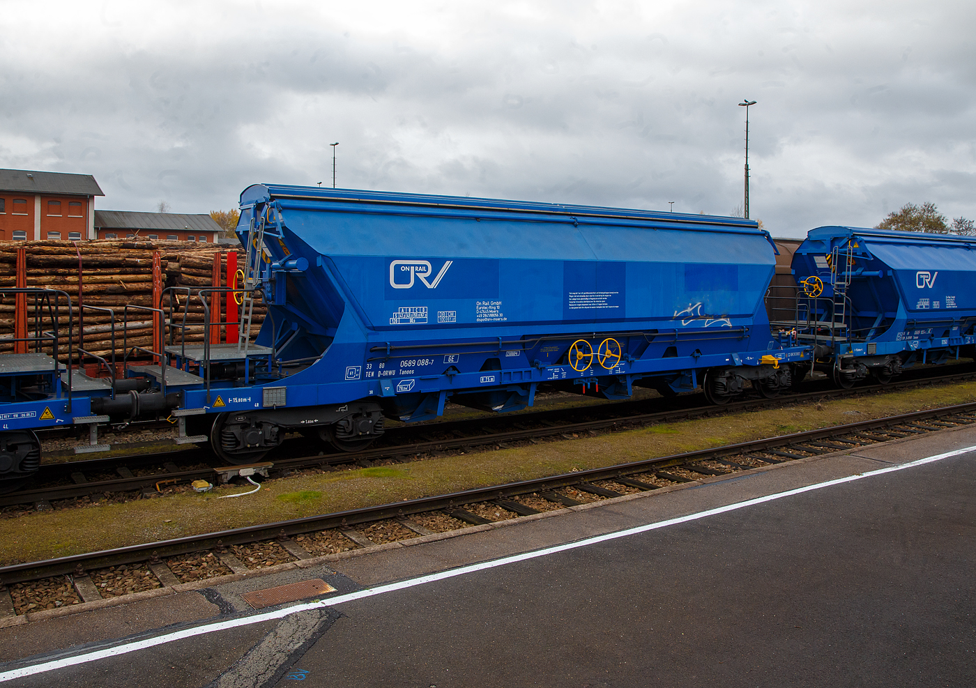 Gedeckter vierachsiger Drehgestell-78m³-Schüttgutwagen mit Schwenkdach und schlagartiger mittigen Schwerkraftentladung (Mittenselbstentladewagen) 33 80 0689 088-7 D-ORWU, der Gattung Tanoos, der Waggonvermietungsfirma On Rail GmbH (Mettman), abgestellt am 24.11.2022 im Bahnhof Schwandorf.

Der Wagen ist für den Transport von nässeempfindlichen Schüttgütern insbesonders korrosiv wirkenden, wie Kali sowie andere Düngemittel und Salze in granulierter Form, geeignet. Aus diesem Grund sind besonders gefährdete Bauteile und Berührungsstellen aus korrosionsfestem Stahl gefertigt. Der Wagenkasten besteht aus einem trichterförmigen Behälter, ist durchgängig und nur zwischen den Auslauföffnungen unterteilt. Die Entladung erfolgt über pyramidenförmige Auslauftrichter, die vier mittig angeordneten Entladeschieber werden paarweise über je ein Handrad betätigt. Alle Ecken und Aussteifungen sind durch Ausrundungen so gestaltet, dass sich nahezu keine Ladegutreste festsetzen können. Schräggestellte Behälterwände haben eine Neigung von 55° bzw. 60° zur Horizontalen. Der Wagenkasten ist so gestaltet, dass er von außen maschinell gereinigt werden kann. Die zweischalige Konzeption des manuell bedienbaren Dachs ist mit einer Kippeinrichtung versehen, die eine optimale Innenreinigung ermöglicht.

TECHNISCHE DATEN:
Hersteller: ELH Waggonbau Niesky GmbH
Spurweite: 1.435 mm
Länge über Puffer : 15.800 mm
Drehzapfenabstand: 10.760 mm
Achsabstand im Drehgestell: 1.800 mm
Laufraddurchmesser: 920 mm (neu)
Eigengewicht: 23.000 kg
Höchstgeschwindigkeit:  100  km/h (beladen) / 120 km/h (leer)
Maximales Ladegewicht: 67,0 t (Streckenklasse D oder höher)
Nat. max. Ladegewicht auch: 61, 0 t (DB Streckenklasse CM - 21 t Radsatzlast)
Kleinster bef. Gleisbogenradius: 75 m
Rauminhalt: 78 m³
Bremse: KE-GP-A (K)
Bremssohle: S517 / C 810
Intern. Verwendungsfähigkeit: TEN-GE

Die Bedeutung der Gattungs- und Kennbuchstaben (hier Tanoos):
T - Wagen mit öffnungsfähigem Dach 
a - mit vier Radsätzen
n - mit vier Radsätzen höchste Lastgrenze über 60 t
oo - mit Schwerkraftentladung, schlagartig, mittig, tiefliegend
s - Höchstgeschwindigkeit 100 km/h (beladen)