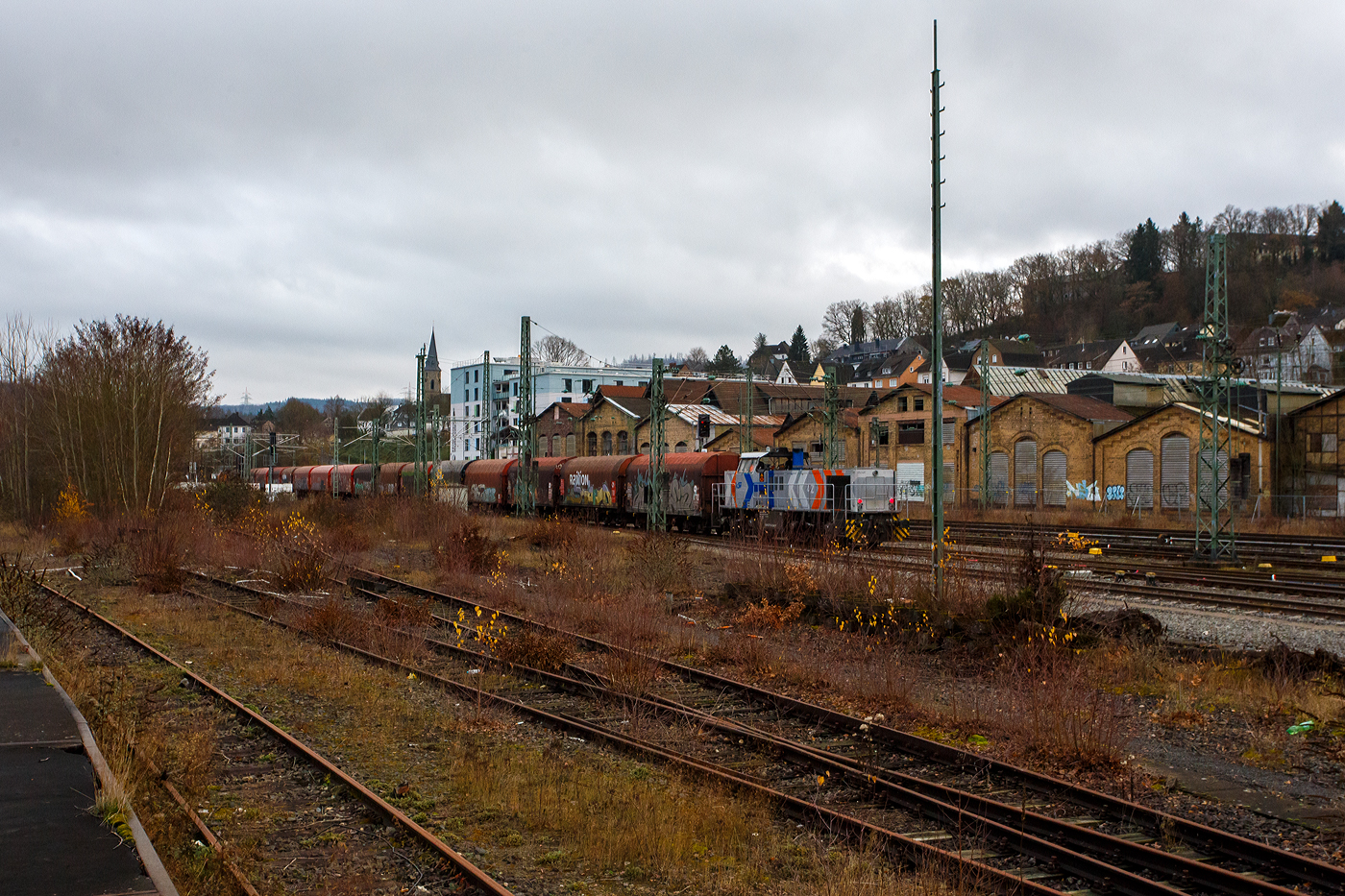 Geführt von der KSW 44 (92 80 1271 004-4 D-KSW), eine MaK G 1000 BB, fährt am 04 Dezember 2025 die KSW (Kreisbahn Siegen-Wittgenstein), im Sandwich mit einem sehr langen und schweren Coilzug, vom Rangierbahnhof Betzdorf/Sieg in Richtung Herdorf zum KSW-Rangierbahnhof (Betriebsstätte FGE - Freien Grunder Eisenbahn) nun los. Hinten hier im Bild nun die nachschiebende KSW 42 bzw. 277 902-3 (92 80 1277 902-3 D-KSW) eine Vossloh MaK G 1700 BB. 

Die Fuhre geht ja über die, nicht elektrifizierte, eingleisige KBS 462 „Hellertalbahn“, da nur eine Güterverkehrsfahrt zwischen den Personenverkehr der RB 96 passt, fährt die KSW lieber eine lange Fuhre im Sandwich. Für eine Lok wäre die Anhängelast eines solchen langen beladenen Coilzuges zu hoch. In Herdorf auf dem Rangierbahnhof der KSW, werden Züge in mehren Teile aufgeteilt und gehen dann über die KSW eigene Strecke NE 447 (ehem. Freien Grunder Eisenbahn nach Neunkirchen-Salchendorf (ehemals Pfannenberger Einigkeit) zu den Produktionshallen der EMW Stahl Service GmbH, ein Geschäftsbereich der SCHÄFER WERKE Gruppe. 

Schon heute werden so dorthin über 300.000 Tonnen Stahl pro Jahr über die Schiene angeliefert, zukünftig sind sogar 600.000 Tonnen geplant.