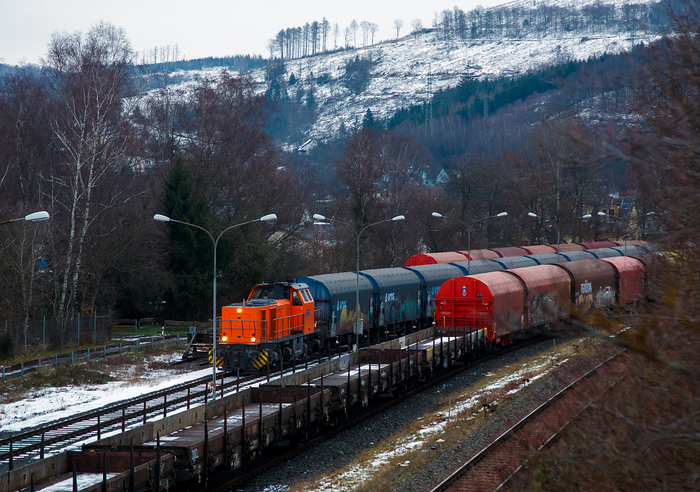 Güterverkehr gibt es noch in Herdorf....
Die KSW 44 (92 80 1271 004-4 D-KSW) eine MaK G 1000 BB der KSW (Kreisbahn Siegen-Wittgenstein), eine MaK G 1000 BB, steht am späten Nachmittag des 24.01.2023 mit einem Coilzug auf dem KSW Rangierbahnhof Herdorf (Freien Grunder Eisenbahn KSW NE447 / DB-Nr. 9275).

Normalerweise läuft der Güterverkehr auf dem Streckenanschnitt Herdorf – Betzdorf, aber der ist bis min. Ende April gesperrt, so muss die KSW den Umweg über Haiger fahren. Aber es ist nicht nur der Umweg, für den Güterverkehr ist noch die Streckenklasse sehr entscheidend und die beträgt bei dem Streckenanschnitt Herdorf – Haiger nur CE (anstatt D4 zwischen Betzdorf und Herdorf). Bei CE beträgt die Radsatzlast max. 20 t bei D4 aber 22,5 t. Dadurch kann ein Coil weniger geladen werden, da man nicht gerademal Coils vierteln kann, ergibt sich daraus ein bis zu 35% geringeres Ladegewicht und ein Mehraufwendung von Waggons.
