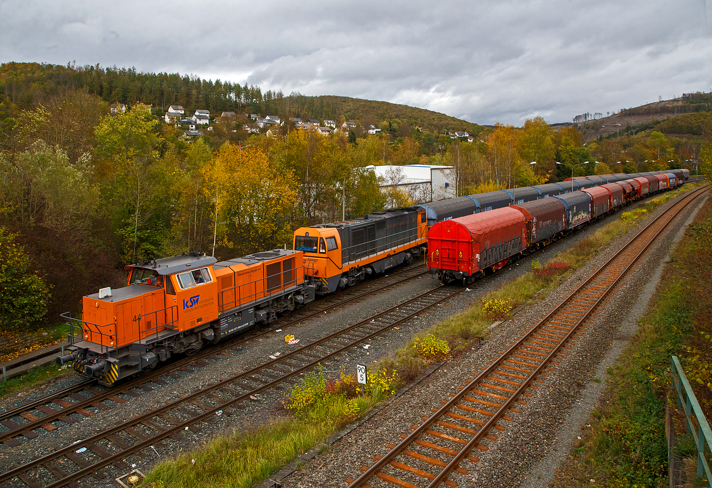 Herdorf 07.11.2022:
Nun hat die KSW 44 (92 80 1271 004-4 D-KSW) eine MaK G 1000 BB, die kalte KSW 43 (92 80 1273 018-2 D-KSW), die asymmetrische Vossloh G 2000 BB, mit einem Übergabezug (leere VTG Coilwagen der Gattung Shimmns-ttu) an den Hacken genommen und zieh den Zug vom KSW Rangierbahnhof Herdorf (Freien Grunder Eisenbahn KSW NE447 / DB-Nr. 9275) in Richtung Betzdorf (Sieg). Warum die KSW 44 die KSW 43 war mir nicht klar.
