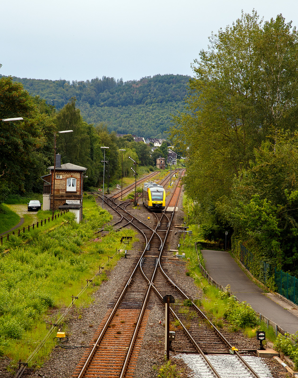 Herdorf 24.08.2023, blick von „Achenbachs Brücke“ auf den Bahnhofsbereich. Der VT 263 (95 80 0648 163-3 D-HEB / 95 80 0648 663-2 D-HEB) ein Alstom Coradia LINT 41 der HLB (Hessische Landesbahn), verlässt als RB 96 „Hellertalbahn“ (Betzdorf – Neunkirchen/Siegerland) den Bahnhof. 

Links die beiden aktiven Stellwerke, vorne das Weichenwärter Stellwerk Herdorf Ost (Ho) und hinten das Fahrdienstleiter Stellwerk Herdorf Hf). 

Rechts die Anschlussstelle zum Rangierbahnhof der KSW (Kreisbahn Siegen-Wittgenstein), Betriebsstätte FGE -Freien Grunder Eisenbahn (KSW NE447 / DB-Nr. 9275). Man kann es sehen, die ersten Meter Gleis ab der Gleissperre hat die KSW erneuern lassen.
