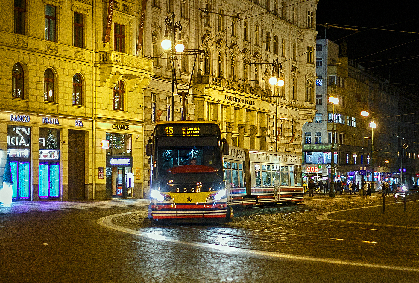 Hier sieht man gut wie die Drehgestelle in der Kurve auslenken....
Stra�enbahn Prag, der Triebwagen DPP 9368, ein dreiteiliger achtachsiger �koda 15T4 bzw. �koda ForCity Alfa Prag, am 22.11.2022, als Linie 9, auf der Senov�n� n�měst� Prag.

Die Stra�enbahn ForCity Alfa Prag ist die weltweit erste in Serie gebaute 100% Niederflurstra�enbahn mit drehbaren Fahrwerken (Drehgestellen) und hat auch als erste getriebelose Motorenantriebe, bei denen alle R�der der vier achsenlosen Drehgestelle mit Permanentmagneten angetrieben werden. Die Endwagen sind mit normalen (achsenlosen) Drehgestellen ausger�stet, die mittleren Drehgestelle sind als achsenlose Jakobsdrehgestelle ausgef�hrt. �ber den Drehgestellen wird der Fu�boden (ohne Stufen) von 350 mm auf 450 mm Bodenh�he angehoben und bildet einen Verbindungsgang mit einer Breite von 700 mm in Bodenn�he.
