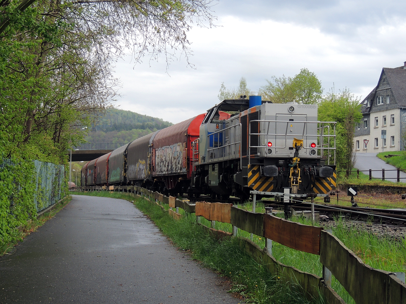 Hochbetrieb in Herdorf am 23 April 2025: 
Durch die vergangenen Osterfeiertage braucht es wohl wieder Nachschub. Die KSW (Kreisbahn Siegen-Wittgenstein) kommt im Sandwich mit einem sehr langen und somit schweren Coilzug, von via Betzdorf/Sieg kommend, und erreicht den KSW-Rangierbahnhof (Betriebsstätte FGE - Freien Grunder Eisenbahn).

Hier am Zugschluss die nachschiebende KSW 47 (92 80 1271 027-5 D-KSW), ex D 2 der HFM, eine Vossloh G 1000 BB, vorne als Zuglok die KSW 44 (92 80 1271 004-4 D-KSW) auch eine MaK G 1000 BB. Im Rbf wird der Zug geteilt, da er für die Weiterfahrt sonst zu lang wäre, und die KSW 44 zieht den ersten Teil weiter zu den Schäfer Werke KG am Pfannenberg in Neunkirchen-Salchendorf. 

Die KSW-Bahnstrecke Herdorf–Pfannenberg-(ehem. Unterwilden) ist eine rund 8 km lange Nebenbahn, bekannt ist sie auch als „Talbahn“. Die Strecke wurde von der 1904 gegründeten Freien Grunder Eisenbahn AG betrieben. Die gebliebenen Gleise und Anlagen sind seit 1970, als Betriebsstätte FGE - Freien Grunder Eisenbahn. Teil der heutigen Kreisbahn Siegen-Wittgenstein.

Später kam dann noch die KSW 43 (92 80 1273 018-2 D-KSW), die asymmetrische Vossloh G 2000 BB, mit einem langen Coilzug von Duisburg an.