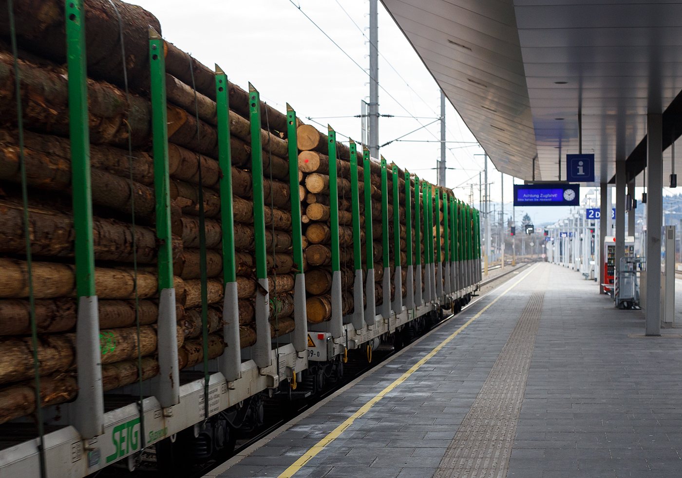 Im Zugverband am 14 Januar 2025 bei der Zugdurchfahrt im Bahnhof Attnang-Puchheim, ein mit Fichtenrundholz beladener vierachsiger Drehgestell-Flachwagen mit Rungen (Rungenwagen) D-SRA 4723 xxx-x der Gattung Snps „SFlexwood“ der SETG.

Die Salzburger EisenbahnTransportLogistik GmbH (SETG) investierte als erste Privatbahn Europa‘s in Neubau-Rungenwaggons. Das österreichische Eisenbahnunternehmen SETG hat gemeinsam mit dem slowakischen Hersteller Tatravagónka a.s. (in Poprad) einen neuen Holztransportwaggon namens Snps „SFlexwood“ entwickelt. Gegenüber herkömmlichen Rungenwagen verfügt die Neukonstruktion mit 8,8 m² über einen deutlich größeren Ladequerschnitt. Die Waggons sind mit Rungen ausgestattet, die sowohl Rundholz- als auch Schnittholztransport ermöglichen. Teile des Rungenschemels sind dazu im Wagenboden integriert, damit beim Schnittholztransport die gesamten Breite zur Verfügung steht. Die Sortimentslängen können 2,5 bis 17 m betragen und die Nutzlast liegt bei 68 t. Durch den Verzicht auf Stirnwände sollen sich bis zu 25% Fahrenergie einsparen lassen. Insgesamt hat die SETG 180 Einheiten des SFlexwood erhalten, remisiert bzw. einstellt sind sie in Deutschland als D-SRA 4723 xxx-x, die internationale Verwendungsfähigkeit ist TEN-CW. 

SFLEXWOOD ist der neue Standard-Holzwaggon: für unterschiedliche Holzlängen, Rund- und Schnittholz, kundenspezifische Zugslängen und maximal ökologisch.

Kenndaten:
Bei 17,20 m Ladelänge und Bauprofil ‚G2‘ waren letztendlich 8,8 m² Ladequerschnitt das Ergebnis detaillierter Planung. Dies stellt den größten Ladequerschnitt aller Rundholzwaggons in Europa dar. Über 68 Tonnen Nutzlast pro Waggon ergeben ein Ladungsgewicht pro Zug von max. 2.380 Tonnen. Je nach Holzbeschaffenheit lassen sich auf einem SFLEXWOOD-Zug somit bis zu 2.500 Festmeter (fm) verladen. Oder bis zu 4.200 Kubikmeter (m³) Schnittholz pro Zug. Soviel wie noch nie auf Zügen in Zentral- und Osteuropa auf Ganzzügen für den Holztransport Platz gefunden hat. Der SFLEXWOOD ist universell in den meisten Ländern Europas einsetzbar – eine wichtige Voraussetzung im flexiblen Holz-Transportmarkt. Die kompakte Länge des SFLEXWOOD-Waggons ermöglicht flexible, kundenspezifische Zuglängen, weniger Rangierbewegungen bei Be- und Entladung und damit eine optimale Auslastung der oft kurzen Lade-/Entladegleise.

Die Wagenkonstruktion ist für eine Achslast von 25 t aus der Sicht der Festigkeit ausgelegt. Der Wagen ist mit einem 70 mm dicken Holzboden und einer Ladekante ausgestattet, die den Wagenfußboden vor Beschädigungen schützt. Der Fußboden erfordert nur geringen Aufwand. Alle Bedienelemente befinden sich unter dem seitlichen Längsträger und sind so vor ungewollten Beschädigungen während der Handhabung mit dem Ladegut geschützt.

Bahngeschichte geschrieben:
Zum ersten Mal seit dem zweiten Weltkrieg hat in Europa eine Privatbahn in den Neubau von Waggons für den Holztransport investiert. Die SETG stärkt damit in ihrem Kernsegment, dem Transport von Forstprodukten, ihre Kompetenz und bietet ihren Kunden ab sofort den maximal größten und maximal flexibelsten Holz-Ganzzug an: SFLEXWOOD.

TECHNISCHE DATEN der SFLEXWOOD-Wagen:
Hersteller: Tatravagónka a.s., in Poprad (Slowakei)
Baujahr: ab 2023
Spurweite: 1.435 mm (Normalspur)
Länge über Puffer: 18.440 mm
Drehzapfenabstand: 12.900 mm
Achsabstand im Drehgestell: 1.800 mm
Laufraddurchmesser: 920 mm (neu) 
Drehgestelltyp: Y25 Ls-K
Ladefläche: 46,8 m²
Ladelänge: 17.200 mm
Höhe der Ladeebene über SOK: 1.260 mm
Anzahl der Rungenpaare: 10
Rungenhöhe: 2.410 mm
Eigengewicht: ca. 22,0 t
Max. Zuladung bei Lastgrenze S: ca. 68,0 t (ab Streckenklasse D)
Max. Geschwindigkeit: 100 km/h (beladen) / 120 km/h (leer)
Max. Radsatzlast: 22,5 t
Intern. Verwendungsfähigkeit: TEN / CW