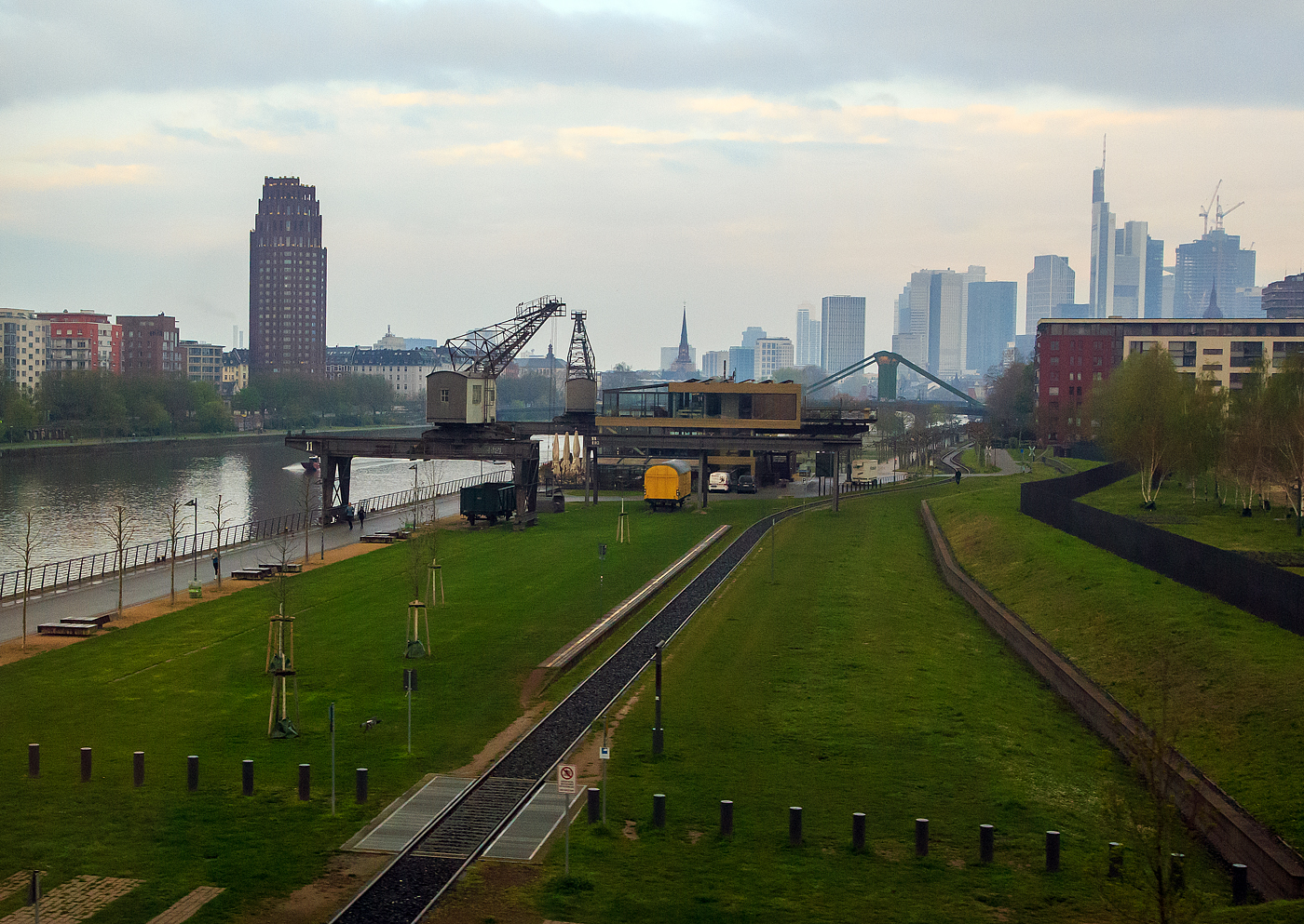 In Frankfurt am Main am Mainufer nahe der Europäische Zentralbank (EZB), wo bis 2004 die Großmarkthalle war (das denkmalgeschützte Gebäude wurde in den Neubau der EZB integriert), gibt es eine schöne Außenanlage „Ruhrorter Werft“, mit Hafenkran, historischen Wagons, Gastronomie und Gleisen der Historischen Eisenbahn Frankfurt, sowie die Haltestelle EZB der Historischen Eisenbahn Frankfurt. Hier am 17.04.2023 aus einem Zug aufgenommen.
