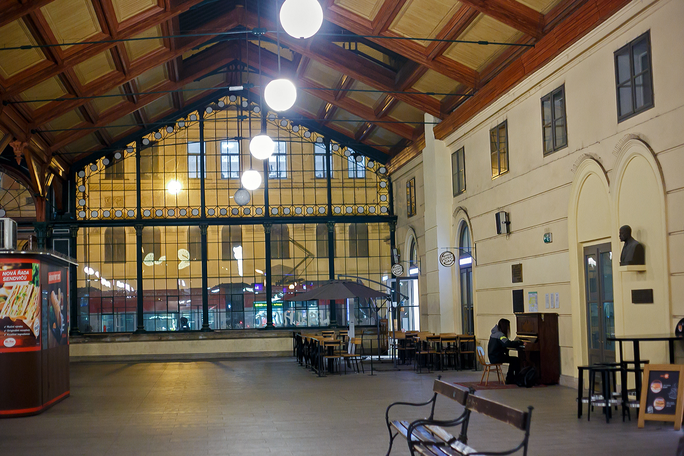 In der sch�nen Empfangshalle vom Prager Masaryk Bahnhof am 22.11.2022, vor dem Bahnhof eine Tram.

Praha Masarykovo n�dra�� (Prag Masaryk Bahnhof)  ist ein wichtiger Regionalbahnhof und fr�herer war er auch Fernbahnhof in Prag. Bei diesem Bahnhof befinden auch direkt vor im Stra�enbahnhaltestellen (etlicher Linien). Erbaut wurde er in den Jahren 1844/45 im Zuge der k.k. N�rdlichen Staatsbahn von Olm�tz, welche bis 1851 von Wien nach Dresden durchgehend in Betrieb genommen wurde. Der Bahnhof ist heute der einzige Kopfbahnhof Prags. Er tr�gt den Namen des ersten Pr�sidenten der Tschechoslowakei Tom� Garrigue Masaryk. 

Die ehemaligen Bahnhofsnamen sind:
 • 1845–1862 Praha / Prag
 • 1862–1919 Praha st�tn� n�dra�� / Prag Staatsbahnhof
 • 1919–1940 Praha Masarykovo n�dra�� (Prag Masarykbahnhof)
 • 1940–1945 Praha Hybernsk� n�dra�� / Prag Hibernerbahnhof
 • 1945–1952 Praha Masarykovo n�dra��
 • 1953–1990 Praha střed (Prag Mitte)
 • seit M�rz 1990 wieder Praha Masarykovo n�dra��

Der Bahnhof Praha Masarykovo n�dra�� gilt als �ltester Bahnhof Prags. Diesen Rang macht ihm nur der heutige Bahnhof Praha-Dejvice streitig, welcher bereits im Jahr 1831 als Endstation der Pferdebahn Prag–Lana entstand, aber damals au�erhalb des Stadtgebiets von Prag lag. Bei seiner Erbauung war er einer der gr��ten Europas.

Der erste (inoffizielle) Zug kam am 4. August 1845 an. Die Er�ffnungsfeiern begannen am 20. August, am 1. September wurde der fahrplanm��ige Zugbetrieb aufgenommen. Zu dieser Zeit gab es eine weitere Haltestelle in Běchovice. Die Strecke Prag–Běchovice war zweigleisig, der Rest der Verbindung nur eingleisig.

Der Bahnhof lag innerhalb der Prager Wallanlagen. Diese wurden zun�chst mit sieben abschlie�baren Toren – eines f�r jedes Gleis – versehen. Erst im Jahr 1874 wurden in diesem Bereich der Stadt die Wallanlagen abgebrochen.

Die Bahnlinie wurde ab 1. Juni 1850, von diesem Bahnhof ausgehend, verl�ngert �ber Hole�ovice bis Bodenbach (heute Děč�n) und am 6. April 1851 bis Dresden.

Am �stlichen Ende des Bahnhofs befand sich eine weitere Station Hrabovka. Von dort gab es ab 1872 Verbindungsb�gen zu den Prager Bahnh�fen Sm�chov, Vy�ehrad und zum heutigen Hauptbahnhof.

Bis zur Er�ffnung des Fernbahnhofs Hole�ovice 1985 war der Bahnhof Masarykovo n�dra�� Endpunkt der Z�ge aus Berlin und Dresden. Ferner war er Richtungswechselbahnhof der Z�ge auf der Relation Berlin-Dresden-Prag-Wien.

Der Bahnhof ist End- bzw. Startpunkt der Bahnstrecken:
S�DC 010, 011 - “Nordbahn“  Česk� Třebov�–Praha
S�DC 090, 091 - “Nordbahn“  Praha–Děč�n 
Beide waren urspr�nglich Teil der k.k. N�rdlichen Staatsbahn.
