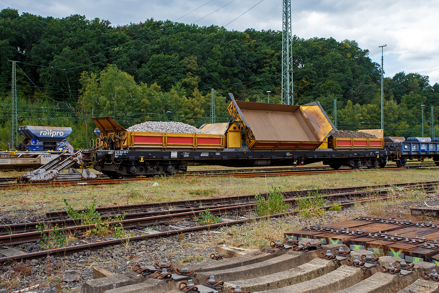 Kippwagen MK 45 DH „LW-Kipper“, 37 80 3832 020-6 D-KAF, der Gattung Rlps, der KAF Falkenhahn Bau AG, Kreuztal (ehemaliger Wagen der Leonhard Weiss) abgestellt am 24 August 2025 in Betzdorf/Sieg.

Der von LEONHARD WEISS entwickelte Kippwagen MK 45 DH „LW-Kipper“, ist f�r den offenen Transport von losen, nicht zu verwehenden Sch�ttg�tern vorgesehen. Dank der niedrigen Bauweise ist die Beladung unter abgeschalteten Oberleitungen gefahrlos m�glich. Die Ladekante ist 2.049 mm �ber Schienenoberkante. Der speziell ausgebildete Bediener ist f�r das Entladen rechts und links vom Gleis verantwortlich. Jeder Wagen ist mit einer eigenst�ndigen Hydraulikanlage ausgestattet, welche von einem Kubota 3-Zyl. Dieselmotor angetrieben wird. So braucht man keine Fremdenergie, wie Strom oder Druckluft von der Lok.

Es wird jeweils eine Mulde pro Wagen gekippt. Es k�nnen bis zu 10 Kippwagen miteinander gekoppelt und �ber ein ansteckbares Bedienpult gemeinsam gesteuert werden. Die Standsicherheit ist in �blichen �berh�hungen und Radien durch eine intelligente Steuerung jederzeit gew�hrleistet. Die Entladezeit betr�gt ca. 10 Minuten f�r alle 3 Mulden.

TECHNISCHE DATEN:
Gattung: Rlps
Spurweite: 1.435 mm (Normalspur)
Achsanzahl: 4 (in zwei Drehgestellen)
L�nge �ber Puffer: 20.740 mm
Drehzapfenabstand: 15.700 mm
Achsabstand im Drehgestell: 1.800 mm
Eigengewicht: 34.450 kg
Max Zuladung: 45,5 t ab Streckenklasse C (8,5 m�)
Muldenma� (L x B x H): 5.000 x 2.480 x 520 mm
H�chstgeschwindigkeit: 100 km/h (leer und beladen)
Bremse: KE-GP-A (max. 68 t)
Kleister befahrbarer Gleisbogen: R = 60 m, (Arbeit R =150 m)
Internationales Profil: G1
Intern. Verwendungsf�higkeit:  RIV

Kippaggregat: Wassergek�hlter 3-Zyl. Dieselmotor Kubota D 1105 mit zwei Hydraulikpumpen und �berdruckventil
Motor-Leistung: 18,5 kW (24,8 PS)
Motor-Hubraum 1.123 l (Bohrung � 78 mm x 78,4 mm Hub)
Tankkapazit�t: 120 l Diesel
Hydr. Tankkapazit�t: 140 l Panolin HLP 46
H�he �ber Schienenoberkante in Transportstellung: 2.690 mm
H�he �ber Schienenoberkante in Kippstellung: 4.009 m
H�he �ber Schienenoberkante in Bordwandh�he: 2.049 mm
Max. Kippwinkel der Mulden: 55�
