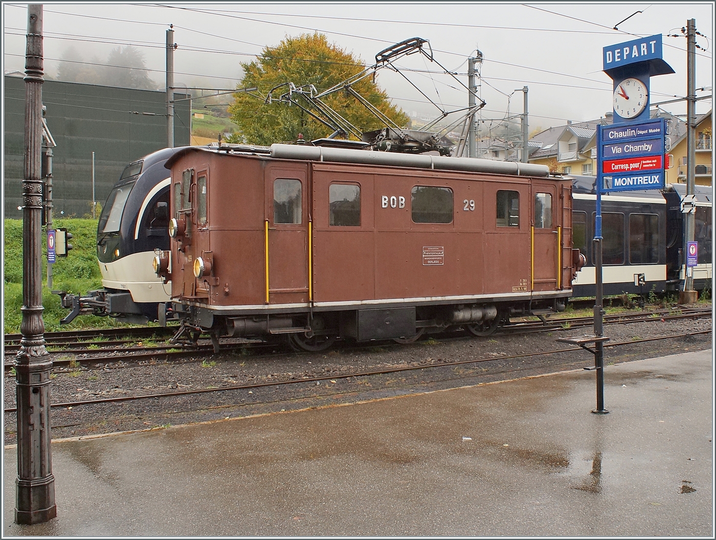 La DER de la Saison / Das Saison Ende der Blonay Chamby Bahn 2025 - Seit einigen Jahren zeigt die Blonay Chamby Bahn zum Saison Ende mit einem verdichteten Fahrplan noch einmal ihre herrlichen Fahrzeuge im Einsatz: Die BOB HGe 3/3 29 der Blonay - Chamby Bahn wartet in Blonay auf ihre Komposition; die Zugzielanzeige für den nächsten Zug nach Chamby (mit Anschluss nach Montreux) gilt aber nicht der BOB HGe 3/3 29 sondern dem (hier nicht zu sehenden) Dm 2/2  Biniou  der Blonay - Chamby Bahn auf Gleis 1 in Blonay.

25. Oktober 2025