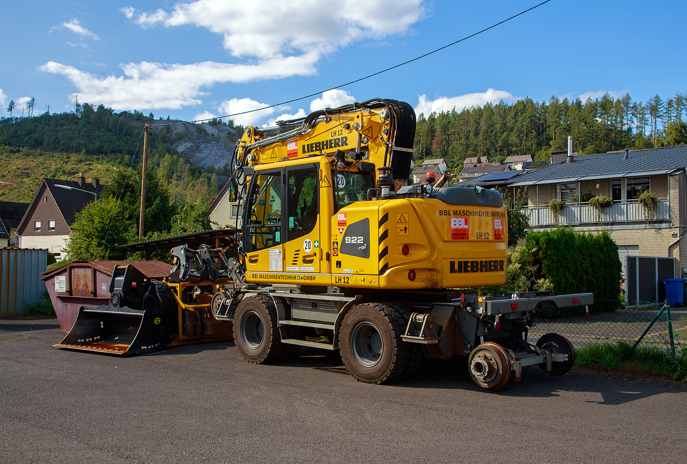 Liebherr Zweiwegebagger A 922 Rail Litronic (Baureihe 1190) mit Abstützpratzen, interne Nr. LH 12 der BBL Maschinentechnik GmbH (Lüneburg), eigestellt durch die SES Aus- und Fortbildung e.K. (Horst / Holstein) unter der Kleinwagen Nr. D-SESAF 99 80 9904 303-1, abgestellt am 26.08.2023 in Herdorf (Ostweg) beim Lokschuppen der KSW, Betriebsstätte FGE -Freien Grunder Eisenbahn.

Der ZW-Bagger wurde 2022 von Liebherr unter der Fabriknummer KLHZ1509JZK137327 gebaut.

Der A 922 Rail Litronic kann als Zweiwegemaschine wahlweise auf der Straße oder auf Eisenbahnschienen eingesetzt werden. An beiden Seiten des Unterwagens ist das Schienenfahrwerk angebracht. Während des Aufgleisens bringt das Schienenfahrwerk die Bereifung auf Schienenniveau, wobei die inneren Räder der Zwillingsbereifung den Fahrantrieb auf der Schiene übernehmen.

TECHNISCHE DATEN:
Spurweite: 1.435 mm
Länge über Puffer: 6.400 mm
Achsabstand (Schiene): 5.700 mm
Laufraddurchmesser (Schiene): 500 mm (neu)
Eigengewicht: 24 t
Motorbauart: wassergekühlter 4Takt - 4-Zylinder-Reihendieselmotor mit Common-Rail-Einspritzsystem, Turbolader und Ladeluftkühlung
Motortyp: Liebherr D924 – FPT 
Motorhubraum: 4,5 Liter
Motorleistung: 120 kW / 163 PS
Höchstgeschwindigkeit (Hg): 19,9 km/h (in Kreuzungen und Weichen 10 km/h)
Zugkraft: 117 kN
Bremse: Kfz.-/SFE-Bremse und Wagonbremsanlage
Zul. Anhängelast: 120 t (ungebremst 40 t)
Zur Mitfahrt zugel. Personenzahl: 1 (und Fahrer)
Antrieb auf Schiene: Über Reibantrieb der Straßenreifen
Hinterer Schwenkradius: 2.000 mm
Max. Neigung: 40 ‰
Max. Gleisüberhöhung: 200 mm

