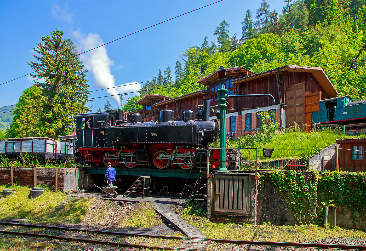Museumsbahn-Romantik pur – Pfingsten 2023 (Samstag 27 bis Montag 29 Mai 2023) fand bei der Museumsbahn Blonay–Chamby das Schweizer Dampffestival 2023 / Festival suisse de la Vapeur 2023 statt.

Bei der Dampflok-Wartungsstelle der Museumsbahn Blonay–Chamby beim Museumsareal in Chaulin steht am 27. Mai 2023 die G 2x2/2 Mallet-Dampflok 105  Todtnau  der Museumsbahn Blonay–Chamby, ex SEG 105  Todtnau .  Links die Strecke hinab nach Blonay, rechts das Stichgleis zum Museum bzw. Depot.

Für den Einsatz auf den Meterspur-Strecken in Frankreich bestellten die Deutschen Heeresfeldbahnen bei der Maschinenbau-Gesellschaft Karlsruhe sieben Mallet-Dampflokomotiven. Aus Zeitgründen wurde keine zeitgemäße neue Serie entwickelt. Man nahm alte Konstruktionsunterlagen als Grundlage. Die Auslieferung erfolgte im August 1918. Bevor die Maschinen HK 94 bis HK 100 (HK = Heeresprüfkommission für Feldbahnen) ihren Einsatzort erreichten, war der I. Weltkrieg (Waffenstillstand von Compiegné am 11. November 1918) jedoch schon beendet. Da sie nicht mehr von den Heeresfeldbahnen benötigt und nicht zum Reparationsgut zugeordnet wurden, übernahm sie das Reichsverwaltungsamt. Dieses verkaufte in den Jahren 1919/1920 die Loks.

Die Lok wurde 1918 von der Maschinenbau-Gesellschaft Karlsruhe unter der Fabriknummer 2051gebaut und von der Heeresprüfkommission für Schmalspurbahnen abgenommen als Lok „HK 95“ abgenommen, wegen dem Kriegsende kam sie auf den Heeresfeldbahnen nicht mehr zum Einsatz. So wurde sie 1919 an die Kleinbahn Voerde-Haspe–Breckerfeld als HVB 28 verkauft. Die Kleinbahn Voerde-Haspe–Breckerfeld wurde elektrifiziert, und die  Nr. 28  wurde 1925 an die Zell-Todtnau-Eisenbahn (in der Nähe von Freiburg) der Süddeutsche Eisenbahn-Gesellschaft (SEG) abgegeben, wo sie die  Nummer 105  -  Todtnau  erhielt. Sie blieb bis zur Streckenstillegung der Linie im Jahre 1968 im Schwarzwald und ging gleich drauf an die Museumsbahn Blonay – Champy.
Es ist noch eine Schwesterlok erhalten geblieben, es ist die 99 5906 der HSB.

Konstruktion:
Das hintere Triebwerk mit den Hochdruckzylindern ist fest im Blechrahmen gelagert. Das vordere Triebwerk mit den Niederdruckzylindern ist mit einem Königszapfen mit dem hinteren Triebwerk verbunden, der genietete Kessel liegt mit Gleitplatten auf ihm auf. Seitliche Blattfedern halten das Triebwerk in einer mittigen Stellung. Beide Triebwerke haben einen Innenrahmen.

Der Dampf wird erst zu den hinteren Zylindern geleitet, von dort gelangt er über flexible Leitungen in die vorderen Zylinder. Alle Zylinder verfügen über Flachschieber und außenliegende Heusinger-Steuerung mit Hängeeisen. Die Loks verfügen über eine Wurfhebel-Handbremse und eine Dampfbremse als Zusatzbremse. Je nach Bahn wurden später Saugluft- oder Druckluftbremse als Zugbremse nachgerüstet. Auf dem Kessel sitzen zwei Sanddome, einer für jedes Triebwerk.

TECHNISCHE DATEN:
Hersteller Maschinenbau-Gesellschaft Karlsruhe (MBK)
Baujahr: 1918
Betriebsgattung: K 44.9
Kurzbezeichnung: B' B n4vt
Spurweite: 1.000 mm
Kurzbezeichnung: B' B n4vt
Länge über Puffer: 9.400 mm
Höhe über SO: 3.800 mm
Achsstand im Triebwerk: 1.400 mm
Treibraddurchmesser: 1.000 mm
Leergewicht: 28,5 t
Dienstgewicht: 34,4 t
Höchstgeschwindigkeit: 30 km/h
indizierte Leistung: 200 kW (270 PS)
Anfahrzugkraft: 47,76 kN
kleinster befahrbarer Gleisbogen: 50 m
Kesselüberdruck: 12 bar
Kohlevorrat : 1,1 t
Wasservorrat: 3,6 m³
Zylinderanzahl: 4
Zylinderdurchmesser: 280 mm (HD) / 425 mm (ND)
Kolbenhub: 500 mm
Bremse: Knorrbremse m. Z., Wurfhebel-Handbremse

Geschichte der Mallet-Lokomotiven:
Der zunehmende Verkehr auf schmalspurigen Eisenbahnen erschloss Mallet ein anderes Wirkungsfeld. Diese Bahnen benötigten stärkere und damit größere Maschinen, als es die engen Kurven der Schmalspurstrecken zuließen. Die einzige Lösung schienen hier Lokomotiven mit schwenkbaren Fahrwerken zu sein. Dazu waren bereits die Bauarten von Fairlie und Meyer verbreitet, die schwenkbare Maschineneinheiten verwendeten. Die einzelnen Einheiten wurden mit Dampf über flexible Verbindungen gespeist, die sich jedoch stets als Schwachpunkt der Maschinen erwiesen. Mallet entwickelte stattdessen eine Bauart mit zwei Fahrwerken, von denen nur das vordere, unter der Rauchkammer befindliche Fahrwerk schwenkbar gelagert war, während der Kessel fest auf dem anderen Fahrwerk ruhte. Damit reduzierte sich die Zahl der flexiblen Verbindungen um die Hälfte. Der wesentliche Unterschied der Konstruktion von Mallet im Vergleich zu den Bauarten Fairlie und Meyer war aber die perfekte Anwendung eines Verbundtriebwerkes. Der Frischdampf wird zunächst zu den Hochdruckzylindern des fest gelagerten Fahrwerks geleitet und nach dem Auslass in die Niederdruckzylinder des vorderen beweglichen Fahrwerks. Die dorthin führende bewegliche Dampfleitungsverbindung war wegen des geringeren Drucks besser beherrschbar als bei reiner Frischdampf-Versorgung. Diese Bauart ließ Mallet sich 1884 patentieren.

Dampflokomotiven haben im Allgemeinen zwei Arbeitszylinder, die Mallet-Loks besitzen diese Einrichtungen doppelt, also 4 Zylinder mit zugehörigen Triebwerksgruppen. Der Abdampf der ersten ist gleichzeitig der Arbeitsdampf der zweiten Zylindergruppe.

Schweizerische Bauartbezeichnung G2 x 2/2, Deutsche Reichsbahn Baureihe 99.590

Mallet-Lokomotive B'B n4vt
- B'B = Dampflokomotive mit 2 Triebwerken, das erste davon beweglich gelagert, zu je 2 Treibachsen
- n4 = Naßdampf und 4 Zylinder
- v = Verbundwirkung zwischen den Hoch- und Niederdruck-Zylindern
- t = Brennstoff und Wasservorräte werden auf der Lokomotive mitgeführt
- (in neuerer Schreibweise wird häufig das  t  weggelassen.
- Bei Angaben ohne  t  handelt es sich dann immer um eine Tenderlok, im Gegensatz dazu  T  = Schlepptenderlok).
