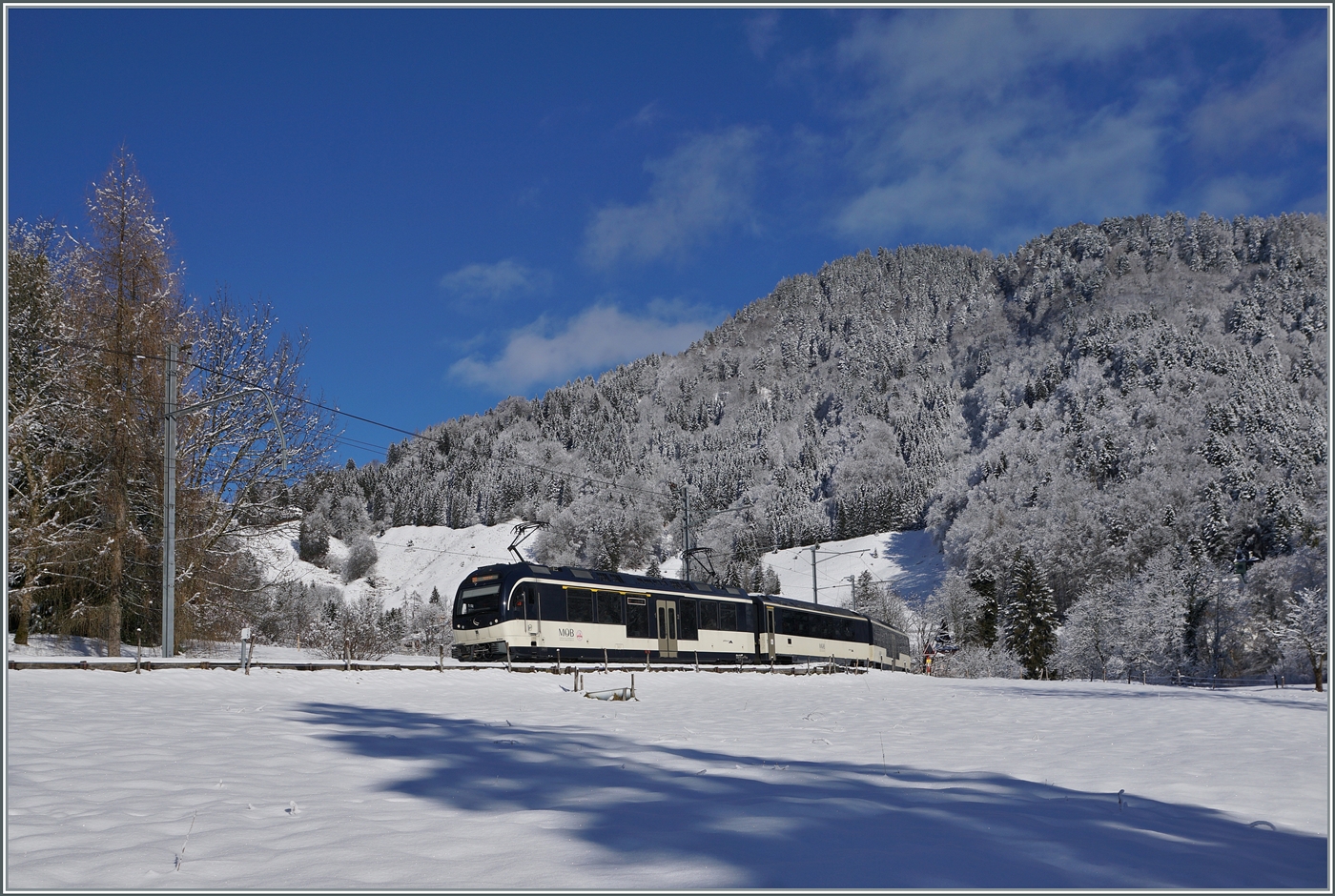 Nachdem es über Nacht geschneit hatte, zeigt sich die Landschaft oberhalb von etwa 800 müM für eine kurze in einem zauberhaften Winterkleid. Grund genug, nach Les Avants zu fahren und die Pracht festzuhalten bevor sie dahinschmilzt. Vor dem Hintergrund verschneiter Wälder sind die beiden MOB Alpina ABe 4/4 9304 und Be 4/4 9204 bei Les Avants dem Regionalzug PE 2215 auf dem Weg von Zweisimmen nach Montreux.

3. Jan.2025