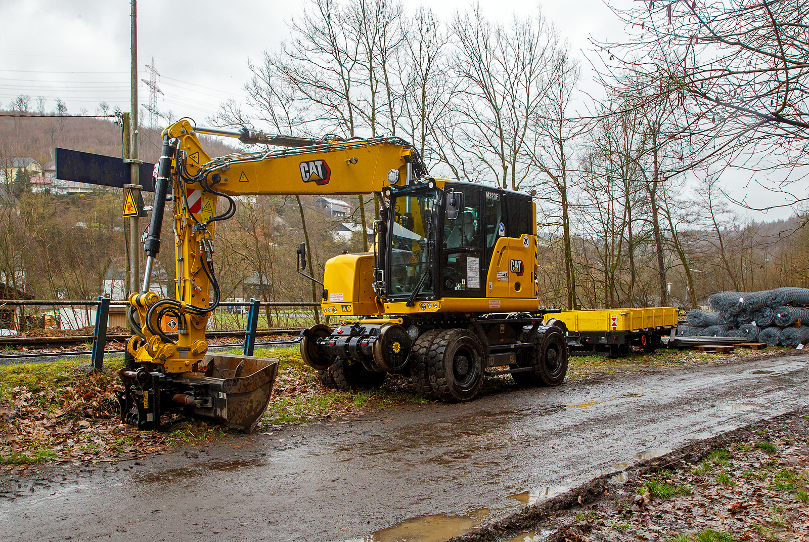 Neuer Zweiwegebagger....
Der Caterpillar CAT M323F Zweiwegebagger mit hydrostatischem Schienenradantrieb (Serien-Nr. RH600 160), Kleinwagen Nr. D-ZBM 99 80 9902 510-3 der ZEPPELIN Baumaschinen GmbH (Garching) ist am 01.04.2023 beim Hp Gr�nebach Ort (an der Hellertalbahn) abgestellt. Dahinter steht noch ein Gleiskraftwagenanh�nger GKW-A und dahinter liegen Stahlnetze und Material wohl f�r die Hangsicherung beim Hp. K�nigstollen.

Der Zweiwegebagger wurde im Juni 2022 unter der Fabrik-Nr. CAT M323FERH600160 gebaut.

Schienenradantrieb
Der CAT Zweiwegebagger mit hydrostatischem Schienenradantrieb (vom franz�sischen Spezialmaschinenbauer UNAC) ist konsequent f�r den Einsatz auf der Schiene entwickelt. Mit seinem kurzen Heck, dem innovativen Radantrieb und Bremssystem f�r alle Gleisr�der und dem ausgefeilten, aber einfach bedienbaren Kontrollsystem erschlie�t der Cat M323F den Anwendern entscheidende Vorteile.Anders als bei den bisher �blichen Zweiwegebaggern bewegt sich die Maschine auf der Schiene damit nicht abgesenkt auf den herk�mmlichen R�dern voran, sondern ohne Bodenkontakt auf den Schienenr�dern selbst. Die hohe Bodenfreiheit gew�hrleistet dabei, dass die Sicherheitseinrichtungen im Gleisbett beim Fahren nicht besch�digt werden. Mit dem Bremssystem im �lbad an beiden Achsen und den Scheibenbremsen f�r alle Gleisr�der gew�hrleistet der Cat M323F sicheren Vortrieb und kraftvolle Beschleunigung bis auf 20 km/h.

Klassische Zweiwegebagger sind vielfach noch mit Reibradantrieb ausgestattet. Die Reifen des Baggers werden dabei auf die Schienen oder Rolle gepresst und �bertragen so die Antriebs- und Bremskr�fte. Die Nachteile: hoher einseitiger Reifenverschlei� und oft Besch�digungen von Sicherheitseinrichtungen im Gleisbett.

Kurzheckbauweise
Durch den kompakten Aufbau und die geringe Heckausladung von nur
1.566 mm kann der Schienenverkehr auf dem Nachbargleis problemlos
weiterlaufen. Auch mit dem optional verf�gbaren Zusatzkontergewicht bleibt der kurze Heckschwenkradius unver�ndert. Trotz des kompakten Hecks bietet die Maschine mit dem robusten Verstellausleger auch auf dem Gleis viel Reichweite und hohes Hubverm�gen.

Die Konstruktionsweise sowie das bis zu 7,5 t schwere Kontergewicht stellen dabei sicher, dass die Maschine dennoch �ber eine hohe Standsicherheit, Reichweite und Hubverm�gen verf�gt.

Motor
Angetrieben wird der neue CAT Zweiwegebagger von einem Vierzylinder-Viertakt-Reihendieselmotor mit zwei Turboladern (Reihenturboaufladung) und Ladeluftk�hlung (TTA) vom Typ CAT C4.4 ACERT TTA, Emissionen EPA Tier 4 Final (USA) bzw. Stufe V (EU) und Dieselpartikelfilter.

Motordaten:
Leistung: 129,4 kW (173 PS)
Maximales Drehmoment: 750 Nm bei 1400 U/min
Nenndrehzahl 2.200 U/min
Bohrung x Hub: 105 x 127 mm
Motorhubraum: 4,4 l
Verdichtungsverh�ltnis: 16,5 :1
Ansaugsystem: Turboladern und Ladeluftk�hlung (TTA)
Verbrennungsverfahren: Direkteinspritzung
Abmessung: 845 x 742 x 868 mm
Gewicht (trocken) 420 kg

Der C4.4-Motor kann entweder mit extrem schwefelarmem Dieselkraftstoff oder mit B20-Biodiesel betrieben werden und erf�llt die Emissionsnormen der EU-Stufe IV. Die Leerlaufabschaltung, die automatische Motordrehzahlregelung und das bedarfsgesteuerte K�hlsystem verringern den Kraftstoffverbrauch.

TECHNISCHE DATEN:
Spurweite: 1.435 mm (Normalspur)
Eigengewicht: 23.400 kg
H�chstgeschwindigkeit: 19,9 km/h (20 km/h auf Stra�e)
Zul. Anh�ngelast: 220 t
Schienenbodenfreiheit: 195 mm
Stra�enbodenfreiheit: 360 mm
Zugkraft auf Stra�e: 104 kN
Zugkraft auf Schiene: 45 kN

Quellen: CAT, ZEPPELIN und Anschriften
