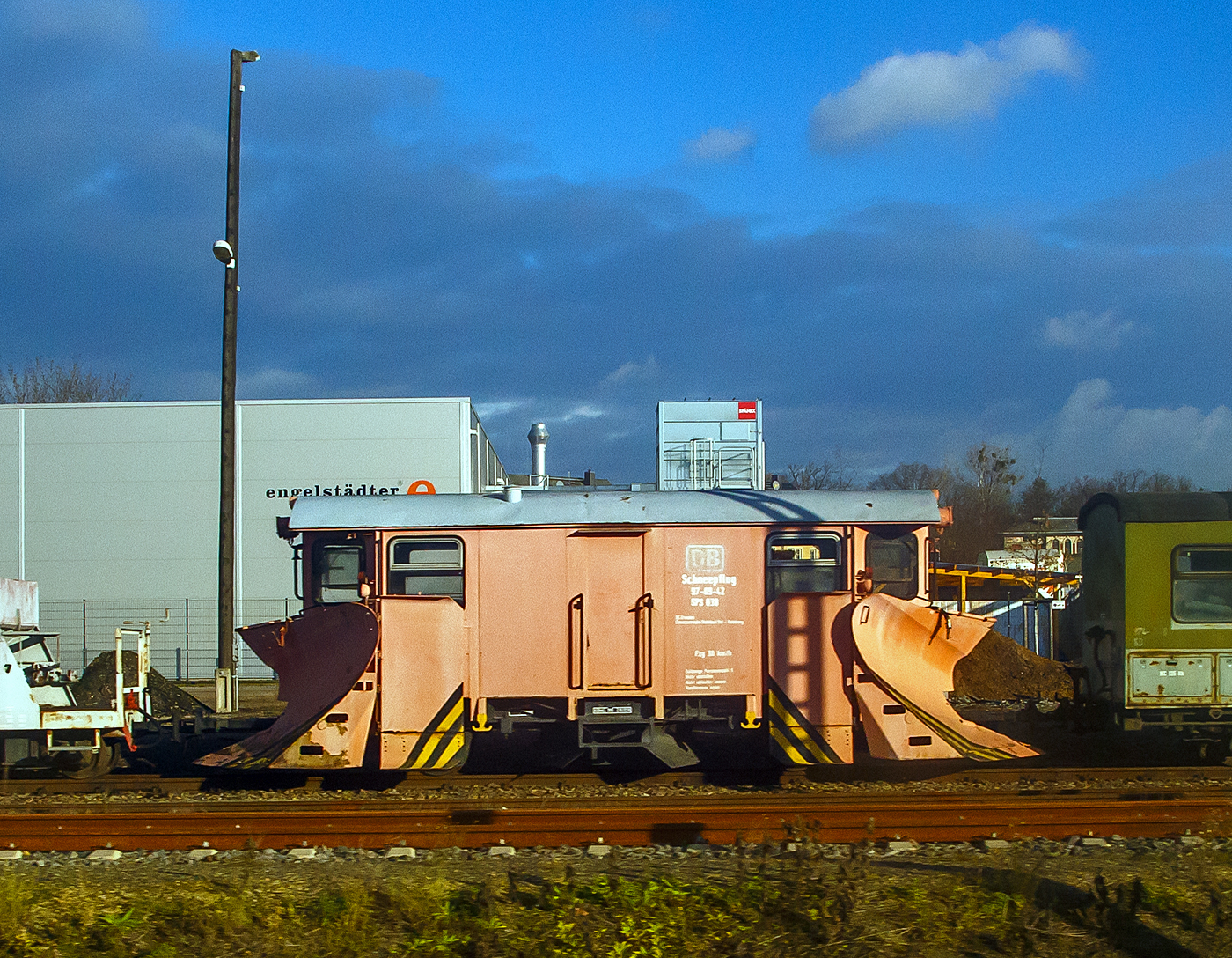 Obwohl die Zugehörigkeit zur DB sehr kurz war, ist dieser Schmalspur-Schneepflug 97-09-42  SPS 038 noch im DB Design.....
Der zweiachsige Schmalspur (750mm) Schneepflug 97-09-40  SPS 036 der Lößnitzgrundbahn (zur SDG - Sächsische Dampfeisenbahngesellschaft mbH), am 08.12.2022 in Radebeul Ost, aufgenommen aus einem IC).

Diese Serie von zweiachsigen nicht selbstfahrenden Schneepflügen (Neubauschneepflug) der Bauart 805 endstanden 1988 bis 1990 im Raw Meiningen eine welche für alle Schmalspurbahnen geeignet waren und nur die Spurweite verändert werden musste. Die Hauptpflugschare können zwischen 40 mm und 130 mm über Schienenoberkante angehoben werden. Außerdem sind zwei kleinere Pflugschare unter dem Wagenboden vorhanden, welche auch zwischen den Schienen räumen können.

TECHNISCHE DATEN:
Bauart: 805
Hersteller: RAW Meiningen
Baujahr: 1989
Spurweite: 750 mm
Achsanzahl: 2
Achsabstand: 4.000 mm
Länge über Kupplung: 9.350 mm
Eigengewicht: 16.800 kg
Höchstgeschwindigkeit.: 30 km/h
Zulässige Personenzahl zur Mitfahrt: 6
Kupplungstyp: Scharfenbergkupplung
