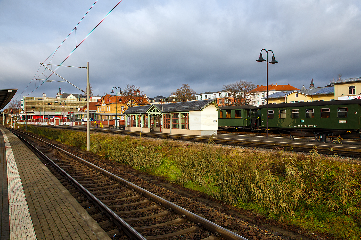 Radebeul Ost den 07.12.2022:
Blick vom Normalspurigen DB Bahnhof auf den Schmalspur Bahnhof der Lößnitzgrundbahn der SDG - Sächsische Dampfeisenbahngesellschaft mbH, mit dem schönen Wartehäuschen am Bahnsteig. Mit der 750 mm Schmalspurbahn, kann man mit Dampfzügen die 16,5 km lange Strecke von Radebeul Ost über Moritzburg nach Radeburg fahren

Wobei nach der deutschen Wiedervereinigung und der folgenden Bahnreform, die Deutschen Bundesbahn und Deutsche Reichsbahn wurden zum 01. Januar 1994 zur Deutsche Bahn AG vereinigt, gehörten  Bahnhof und die Schmalspur Bahn, bis Juni 2004 zur DB AG. Im Juni 2004 ging die Strecke gemeinsam mit der Weißeritztalbahn an die BVO Bahn GmbH (seit 2007 dann SDG - Sächsische Dampfeisenbahngesellschaft). Die SDG seit Anfang 2019 den Verkehrsverbünden Mittelsachsen (VMS) 1/3 und Oberelbe (VVO) 2/3.