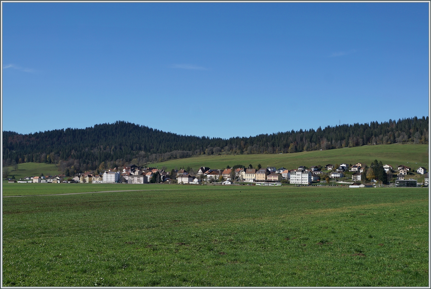 Schon fast ein Zugsuchbild: der Blick gleitet über das weite Jura Hochtal nach La Sagne. Dort ist ein TransN cmn ABe 4/8 auf der Fahrt als R22 zu erkennen. 

28. Okt. 2024  