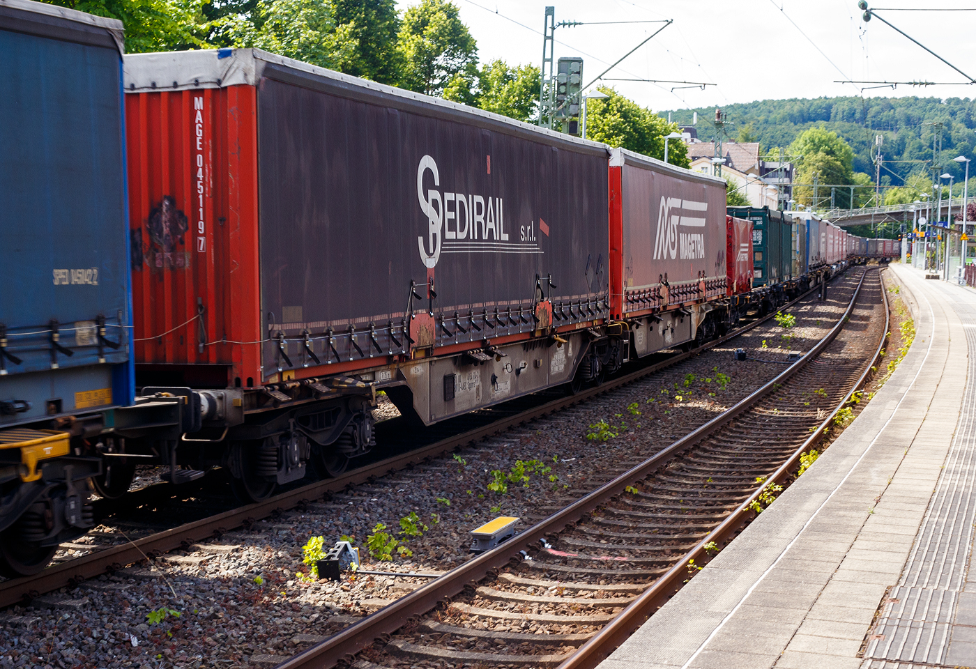 Sechsachsiger Drehgestell-Gelenk-Containertragwageneinheit 90´, 31 80 4954 614-2 D-AAEC, der Gattung Sggmrs 90´179 (VTG-Typ I71.090), der VTG Rail Europe GmbH, Hamburg (ehemaliger Wagen der Ahaus Alstätter Eisenbahn Cargo AG), am 05 Juli 2025 im Zugverband bei der Zugdurchfahrt in Kirchen/Sieg, hier beladen mit zwei Sattelauflieger-Wechselbrücken.

Diese Gelenkwagen mit sechs Radsätzen sind für den Transport von Großcontainern und Wechselbehältern vorgesehen. Auf den Außenlangträger des Wagens befinden sich für jede vorgesehene Ladeposition feste und klappbare Aufsetzzapfen zum Festlegen der Ladungseinheiten (gemäß UIC- Merkblatt 592-1 und 2) in verschiedenen Kombinationen.

TECHNISCHE DATEN:
Spurweite: 1.435 mm (Normalspur)
Anzahl der Achsen: 6 in drei Drehgestellen
Länge über Puffer: 29.590 mm
Drehzapfenabstand: 2 x 11.995mm
Achsabstand im Drehgestell: 1.800mm
Laufraddurchmesser: 920 mm (neu)
Ladelänge: 2 x 13.820 mm (2 x 45 = 90 ft)
Höhe der Ladeebene über SOK: 1.155 mm
Höchstgeschwindigkeit: 100 km/h Lastgrenze S / 120 km/h bei Lastgrenze SS und leer)
Max. Zuladung bei Lastgrenze S: 106,0 t (ab Streckenklasse D)
Max. Zuladung bei Lastgrenze SS: 67,0 t (ab Streckenklasse A)
Eigengewicht: ca. 29.000 kg
Kleinster bef. Gleisbogenradius: R 75 m (im Zugverband R 150 m)
Handbremse: Ja
Intern. Verwendungsfähigkeit: RIV