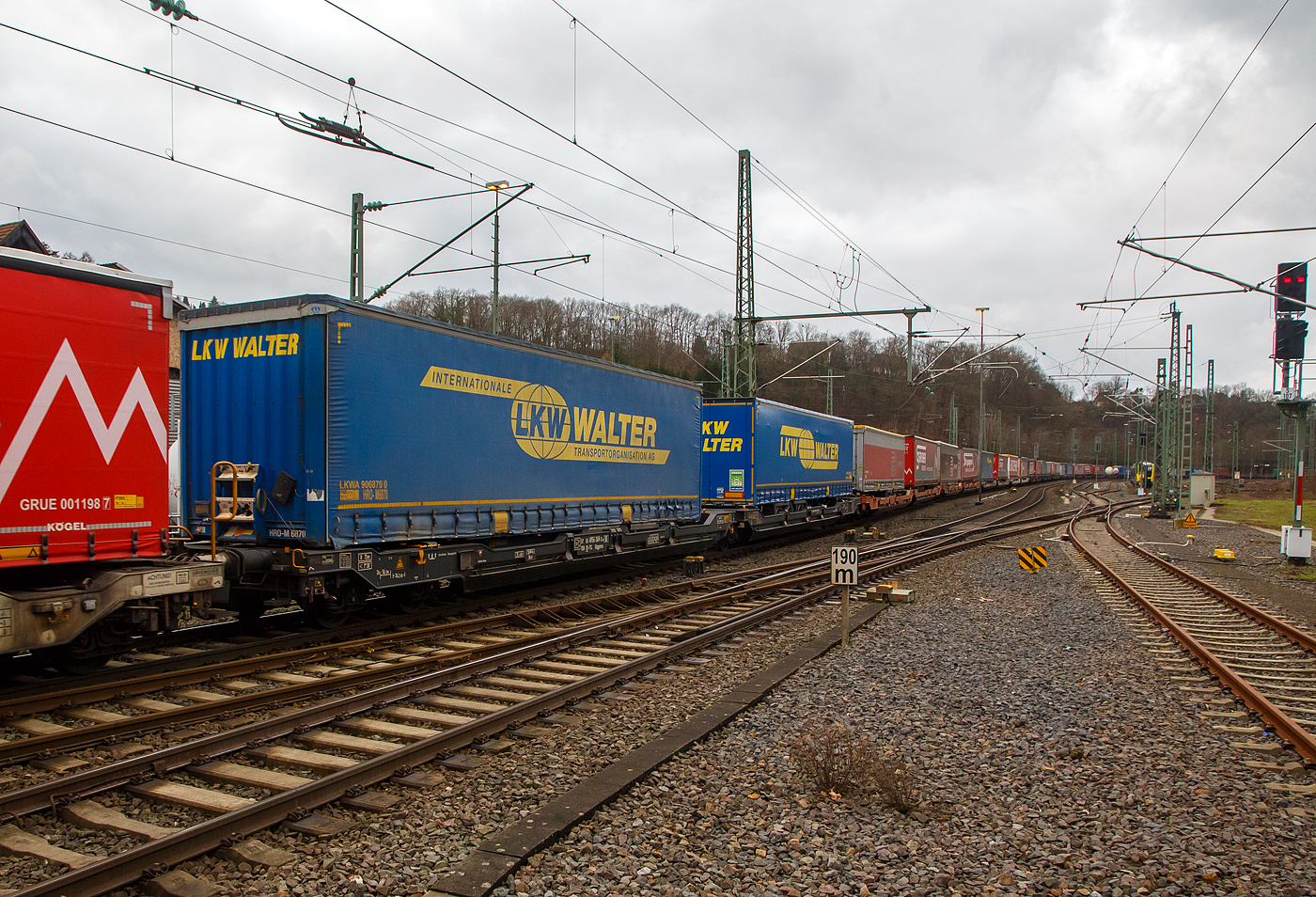 Sechsachsiger Gelenk-Taschenwagen (Doppeltaschenwagen T3000e), 37 85 4956 269-9 CH-TXL, der Gattung Sdggmrss, der TX Logistik AG (Troisdorf), am 30.01.2023 im Zugverband bei der Durchfahrt in Betzdorf (Sieg), hier beladen mit zwei Sattelanhängern von LKW Walter. Die TXL gehört seit 2017 zu 100 Prozent der Mercitalia Gruppe, einer Tochtergesellschaft der Ferrovie delle Stato Italiane. 

Diese Wagen vom Typ T3000e wurde von Tatravagónka a.s. in Poprad (Slowakei) ab 2015 gebaut, die Entwicklung und Konstruktion ist von der  Ferriere Cattaneo SA in Giubiasco (Schweiz). Baugleiche Wagen sind auch bei anderen Halteren im Einsatz, die jeweils die Gattungskennzahl 4956 haben. Mögliche Ladeeinheiten sind zwei kranmanipulierbare Sattelaufliegern oder alternativ bis zu vier Wechselbrücken und/oder Container. Dafür besitzt der Wagen einen dreifach verstellbaren Stützbock sowie für die Ladungseinheiten feste und klappbare Aufsetzzapfen auf den Langträgern. Das maximale Zuladegewicht beträgt für Sattelauflieger 2 × 40 t; die Basishöhe liegt bei 270 mm über SO.

TECHNISCHE DATEN:
Spurweite: 1.435 mm
Länge über Puffer: 34.200 mm
Drehzapfenabstand: 2 x 14.200 mm
Achsabstand in den Drehgestellen: 1.800 mm
Laufraddurchmesser: 920 mm (neu) / 860 mm (abgenutzt)
Ladelänge: 2 × 16.185 mm
Eigengewicht: 35.000 kg
Max. Zuladung bei Lastgrenze S: 100,0 t (ab Streckenklasse D)
Max. Zuladung bei Lastgrenze SS: 85,0 t (ab Streckenklasse C)
Max. Geschwindigkeit: 100 km/h (bei Lastgrenze S) / 120 km/h (bei Lastgrenze SS und leer)
Kleinster  befahrbarer Kurvenradius: R 75 m (R 150 m im Zugverband)
Intern. Verwendungsfähigkeit: TEN – GE

Ob es sich um kranmanipulierbare Sattelauflieger handelt, kann man gut an den zwei gelben Rechtecken, unten am Rahmen erkennen. Dort befinden sich die Anschlagpunkte.

Es gibt aber heute auch Systeme für nicht kranbare Sattelauflieger, wie das System NiKRASA der TX Logistik, damit werden diese kranbar und können in Taschenwagen (wie o.g.) verladen werden. Bei anderen Systemen wie LOHR, CargoBeamer oder HELROM-Trailer-Rail sind keine Krane oder Reachstacker, es sind aber besondere Systemeienge Wagen notwendig. Hervorzuheben ist hier das HELROM-System, es genügt eine asphaltierte Fläche neben dem Gleis.
