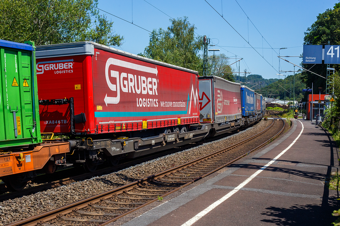 Sechsachsiger Gelenk-Taschenwagen (Doppeltaschenwagen T3000e), 37 80 4993 400-3 D-WASCO, der Gattung Sdggmrs (T3000e), der WASCOSA AG (Luzern), am 25 Juni 2024 im Zugverband bei der Durchfahrt in Scheuerfeld (Sieg), hier beladen mit zwei Sattelanh�ngern (Trailer).

Diese Wagen vom Typ T3000e wurde von Tatravag�nka a.s. in Poprad (Slowakei) ab 2015 gebaut, die Entwicklung und Konstruktion ist von der Ferriere Cattaneo SA in Giubiasco (Schweiz). Baugleiche Wagen sind auch bei anderen Halteren im Einsatz, die jeweils die Gattungskennzahl 4956 haben. M�gliche Ladeeinheiten sind zwei kranmanipulierbare Sattelaufliegern oder alternativ bis zu vier Wechselbr�cken und/oder Container in verschiedenen L�ngen (20′ bis 45′). Daf�r besitzt der Wagen einen dreifach verstellbaren St�tzbock sowie f�r die Ladungseinheiten feste und klappbare Aufsetzzapfen auf den Langtr�gern. Das maximale Zuladegewicht betr�gt f�r Sattelauflieger 2 � 40 t; die Basish�he liegt bei 270 mm �ber SO.

TECHNISCHE DATEN:
Spurweite: 1.435 mm (Normalspur)
L�nge �ber Puffer: 34.200 mm
Drehzapfenabstand: 2 x 14.200 mm
Achsabstand in den Drehgestellen: 1.800 mm
Laufraddurchmesser: 920 mm (neu) / 860 mm (abgenutzt)
Drehgestelltyp: 1 x Y25Ls(s)i1f, 2 x Y25Lssi1-K
Ladel�nge: 2 � 16.185 mm
H�he der Ladefl�che f�r Container: 1.155 mm
Eigengewicht: 34.300 kg
Max. Zuladung bei Lastgrenze S: 100,7 t (ab Streckenklasse D)
Max. Geschwindigkeit: 100 km/h (beladen) / 120 km/h (leer)
Bremse: 2 x DK-GP-A (K)
Bremssohle: Jurid 816 M
Radsatz: BA 004
Handbremse: am mittleren Drehgestell
Kleinster befahrbarer Kurvenradius: R 75 m (R 150 m im Zugverband)
Intern. Verwendungsf�higkeit: TEN  GE / G1