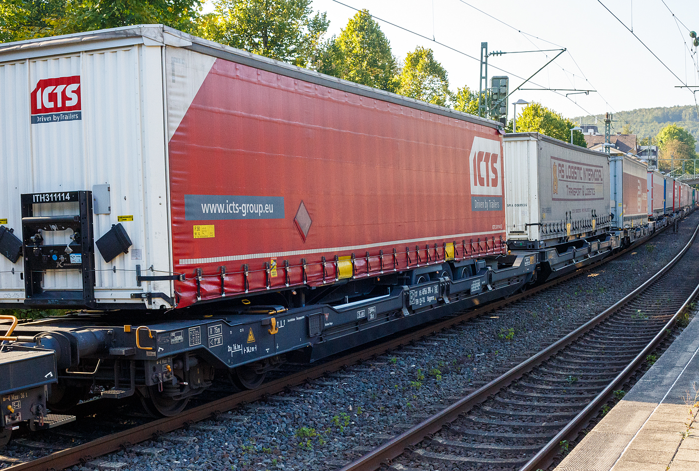 Sechsachsiger Gelenk-Taschenwagen (Doppeltaschenwagen T3000e), 37 85 4956 390-6 CH-TXL, der Gattung Sdggmrss (T3000e), der TX Logistik AG (Troisdorf), am 17 September 2024 im Zugverband bei der Durchfahrt im Bahnhof Kirchen (Sieg), hier beladen mit zwei Sattelanhängern (Trailer). Die TXL gehört seit 2017 zu 100 Prozent der Mercitalia Gruppe, einer Tochtergesellschaft der Ferrovie delle Stato Italiane.

Diese Wagen vom Typ T3000e wurde von Tatravagónka a.s. in Poprad (Slowakei) ab 2015 gebaut, die Entwicklung und Konstruktion ist von der Ferriere Cattaneo SA in Giubiasco (Schweiz). Baugleiche Wagen sind auch bei anderen Halteren im Einsatz, die jeweils die Gattungskennzahl 4956 haben. Mögliche Ladeeinheiten sind zwei kranmanipulierbare Sattelaufliegern oder alternativ bis zu vier Wechselbrücken und/oder Container. Dafür besitzt der Wagen einen dreifach verstellbaren Stützbock sowie für die Ladungseinheiten feste und klappbare Aufsetzzapfen auf den Langträgern. Das maximale Zuladegewicht beträgt für Sattelauflieger 2 × 40 t; die Basishöhe liegt bei 270 mm über SO.

TECHNISCHE DATEN:
Spurweite: 1.435 mm (Normalspur)
Länge über Puffer: 34.200 mm
Drehzapfenabstand: 2 x 14.200 mm
Achsabstand in den Drehgestellen: 1.800 mm
Laufraddurchmesser: 920 mm (neu) / 860 mm (abgenutzt)
Drehgestelltyp: 1 x Y25Ls(s)i1f, 2 x Y25Lssi1-K
Ladelänge: 2 × 16.185 mm
Höhe der Ladefläche für Container: 1.155 mm
Eigengewicht: 35.000 kg
Max. Zuladung bei Lastgrenze S: 100,0 t (ab Streckenklasse D)
Max. Zuladung bei Lastgrenze SS: 85,0 t (ab Streckenklasse C)
Max. Geschwindigkeit: 100 km/h (bei Lastgrenze S) / 120 km/h (bei Lastgrenze SS und leer)
Bremse: 2 x DK-GP-A (K)
Bremssohle: Jurid 816 M
Handbremse: am mittleren Drehgestell
Kleinster befahrbarer Kurvenradius: R 75 m (R 150 m im Zugverband)
Intern. Verwendungsfähigkeit: TEN  GE / G1