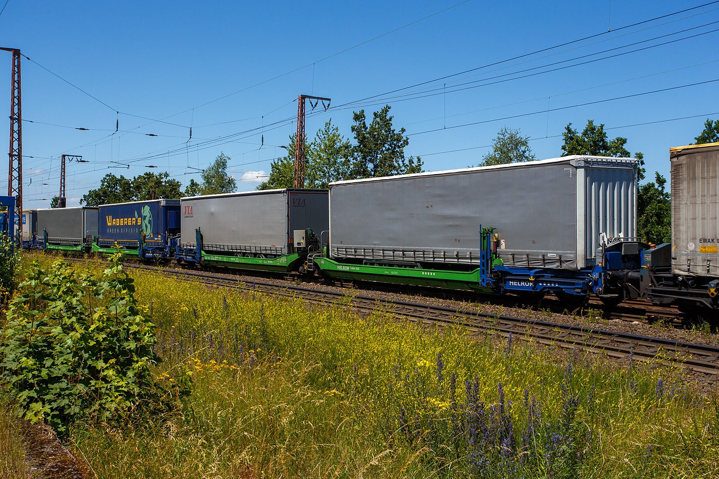 Spezieller sechsachsiger Gelenk-Taschenwagen System HELROM, 33 80 4878 075-1 D-HELR, der Gattung Sdmrs, der HELROM Trailer Rail am 28 Juni 2024 im Zugverband bei der Durchfahrt in Rudersdorf (Kreis Siegen).

Der Clou bei HELROM sind neuartige Transportwaggons, die keine teuren Kran- oder Verladeeinrichtungen brauchen. Dieses Megaswing-System ist ein spezieller Taschenwagen mit schwenkbaren Aufnahmewannen für Sattelauflieger. Hydraulikstützen dienen als Stabilisierung, wenn die Wanne nach links oder rechts ausschwenkt. Die Beladung der Wanne mit einem Sattelauflieger erfolgt rückwärts. Nach Absatteln des Sattelaufliegers wird die Wanne angehoben und schwenkt wieder ein. Der Sattelauflieger wird leicht abgesenkt und mit dem Waggon fest verbunden, er ist nun auf dem Waggon sicher verstaut. Die Technik ist im Waggon verbaut.

TECHNISCHE DATEN:
Hersteller: Gök Yapi  (Türkei)
Spurweite: 1.435 mm
Länge über Puffer: 34.230 mm
Drehzapfenabstand: 2 x 14.200 mm
Achsabstand im Drehgestellen: 1.800 mm
Laufraddurchmesser: 920 mm (neu)
Eigengewicht: 45.700 kg 
Max. Zuladung bei Lastgrenze: 76,0 t (ab Streckenklasse D)
Max. Geschwindigkeit: 100 km/h (beladen) / 120 km/h (leer)
Kleinster befahrbarer Gleisbogen: R 75 m
Bremse: 2 x MH-GP-A (K)
Bremssohle: Cosid 810
Feststellbremse: Ja (auf ein Drehgestell)
Intern. Verwendungsfähigkeit: TEN-GE