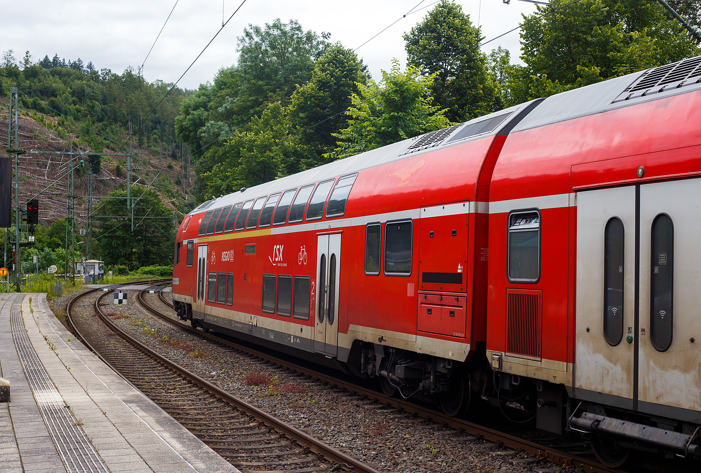 Steuerwagen voraus verlässt der RE 9 rsx - Rhein-Sieg-Express (Siegen – Köln – Aachen) am 21 Juni 2024 den Bahnhof Kirchen/Sieg. Vorne der klimatisierte 1./2. Klasse Doppelstock-Steuerwagen (DoSto-Steuerwagen) ist der D-DB 50 80 86-81 118-1 der Gattung DABpbzfa 767.3. Von der Bauart 767.3 gibt es auch nur 2 Stück diesen und den 119-9 beide sind beim Rhein-Sieg-Express (RE 9) im Einsatz. Schublok war die 146 005-4 der DB Regio NRW.

TECHNISCHE DATEN vom Steuerwagen:
Hersteller: Bombardier Werk Görlitz, ex Deutsche Waggonbau AG (DWA)
Baujahr: 2010
Spurweite: 1.435 mm
Länge über Puffer: 27.270 mm
Wagenkastenlänge: 26.660 mm
Wagenkastenbreite: 2.784 mm
Höhe über Schienenoberkante: 4.631 mm
Drehzapfenabstand: 20.000 mm
Achsstand im Drehgestell: 2.500 mm
Drehgestellbauart: Görlitz VIII
Leergewicht: 53 t
Höchstgeschwindigkeit: 160 km/h
Bremsbauart: KE-PR-A-Mg-mZ (D)
Sitzplätze: 38 (1.Klasse) / 41 (2. Klasse)
Toiletten: 1, behindertengerecht, geschlossenes System
Bemerkungen: 2 Mehrzweckabteil, 1 Dienstraum, uneingeschränkt dieselloktauglich

Auffällig ist das die Doppelstockgarnituren zurzeit mit sechs Dosto-Wagen gefahren werden, anstelle der ansonsten mit fünf Wagen. Ob dies der Fußball EM geschuldet ist, weiß ich aber nicht.
