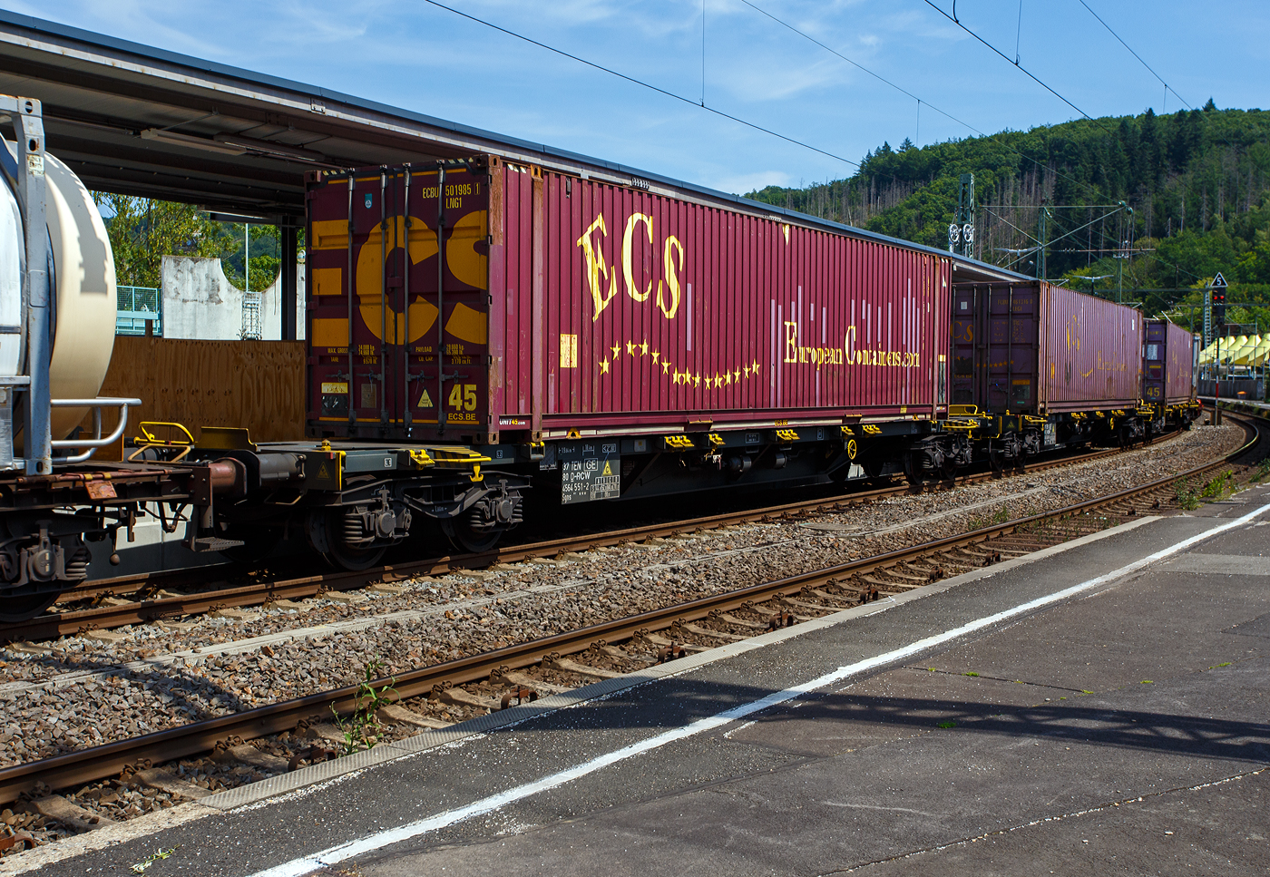Vierachsiger Drehgestell-Containertragwagen, 37 80 4564 551-2 D-RCW, der Gattung Sgns M14 (60´), der RCW – Rail Cargo Group, am 19 Juli 2025 im Zugverband bei der Durchfahrt in Betzdorf/Sieg.

Der Wagen ist im Rahmen der neuen Tragwagenkonzeption für den Transport von Containern (Ct) in Zügen des kombinierten Ladungsverkehrs vorgesehen. Für den Transport von Containern bis insgesamt 60 Fuß Länge sind, auf den Außenlangträgern des Wagens, 28 feste bzw. klappbare Containerzapfen vorhanden. Er ist ein “Allround”-Wagen für den Intermodalverkehr, mit einem idealen Ladegewicht von 70 t. Er ist sehr gut geeignet für maritime Container, Tankcontainer und Wechselbehälter.

Das Untergestell ist eine verwindungsweiche, geschweißte Rahmenkonstruktion aus Walz- und Blechprofilen, gebildet aus den Kopfstücken, den Hauptquerträgern und den äußeren Langträgern.

TECHNISCHE DATEN:
Spurweite: 1.435 mm (Normalspur)
Länge über Puffer: 19.640 mm
Drehzapfenabstand: 14.200 mm
Radsatzstand in den Drehgestellen: 1.800 mm
Ladelänge: 18.400 mm (60 ft)
Höhe der Ladeebene für Container über S.O.: 1.155 mm
Drehgestell-Bauart: Y25 Ls(s)d1
Raddurchmesser: 920 mm (neu) / 860 mm (abgenutzt
Eigengewicht: ca. 20.000 kg
Max. Zuladung bei Lastgrenze S: 70,0 t (ab Streckenklasse D)
Max. Geschwindigkeit: 100 km/h (beladen) / 120 km/h (leer)
Bremse: KE-GP-A (K)
Bremssohle: Jurid 816M 320
Handbremse: Fbr
Verwendungsfähigkeit: TEN-GE
