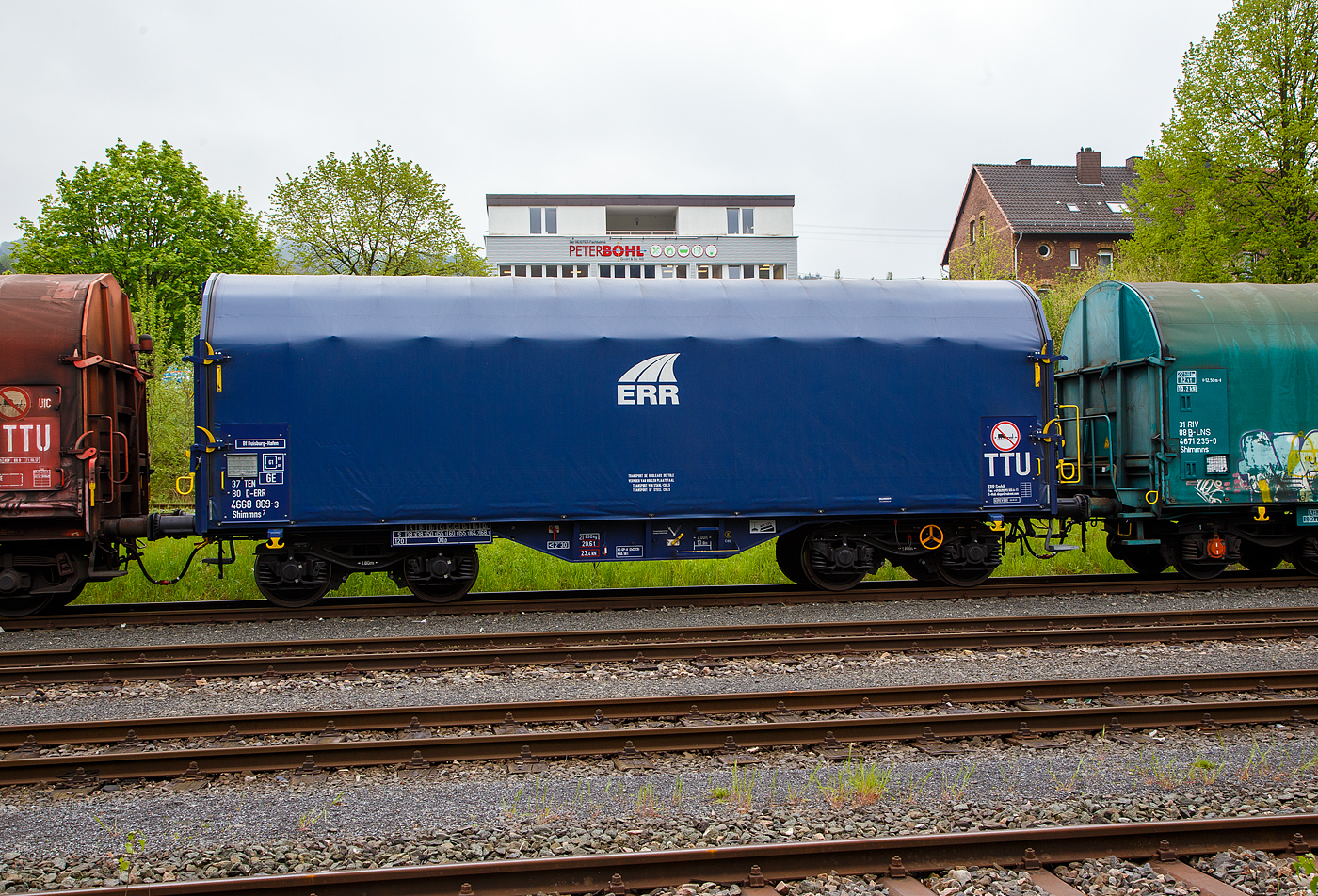 Vierachsiger Drehgestell-Flachwagen mit verschiebbarem Planenverdeck und Lademulden für Coiltransporte, 37 80 4668 869-3 D-ERR, der Gattung Shimmns7 (-ttu), der ERR European Rail Rent GmbH, am 08.05.2023 im Zugverband abgestellt auf dem Betriebsbereich Freien Grunder Eisenbahn der KSW in Herdorf.

Diese Wagen sind speziell für den Transport witterungsempfindlicher Blechrollen (Coils) bestimmt. Er besitzt feste Stirnwände, 5 fest im Untergestell eingebaute Lademulden. Die Wagenabdeckung erfolgt mit einer PVC-beschichteten Gewebeplane, die auf 11 Rohrrahmen aufliegt. Über Laufwagen ist das Planendach in Wagenlängsrichtung verschiebbar. Die Verriegelung des Planendaches an den Stirnwänden erfolgt über eine 4-Punkt-Zentralverriegelung, die sowohl vom Erdboden als auch von der Rampe aus bedient werden kann. Das Planenverdeck lässt sich an einem Wagenende so weit zusammenschieben, dass ca. 2/3 der Ladefläche zur Beladung freigegeben wird. Hierdurch ist eine einfache Beladung des Wagens sowohl von oben als auch von der Seite aus möglich.

TECHNISCHE DATEN:
Spurweite: 1.435 mm
Achsanzahl: 4 (in 2 Drehgestelle)
Länge über Puffer: 12.040 mm
Länge der Ladefläche: 10.800 mm
Drehzapfenabstand: 7.000 mm
Achsabstand im Drehgestell: 1.800 mm
Eigengewicht: 21.890 kg
Höchstgeschwindigkeit: 100 km/h (beladen) / 120 km/h (leer)
Maximales Ladegewicht: 68,1 t (ab Streckenklasse D4)
Kleinster bef. Gleisbogenradius: 35 m
Bauart der Bremse: KE-GP-A (K)
Bremssohle: C 810
Intern. Verwendungsfähigkeit: TEN – GE
