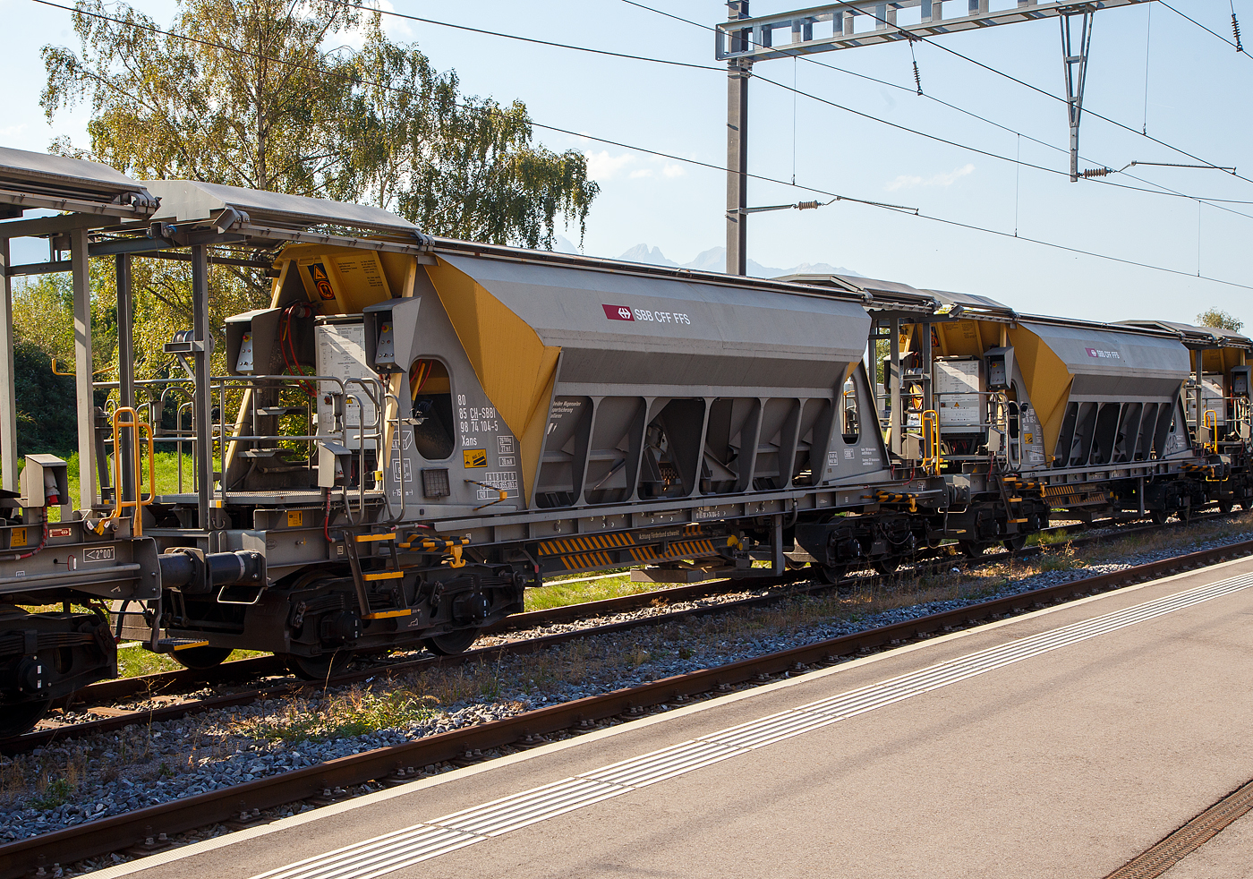 Vierachsiger Drehgestell Schotter-Kieswagen (Planum-Kiessandwagen), Xans 80 85 98 74 104-5 CH-SBBI, der SBB Infrastruktur abgestellt am 10.09.2023 beim Bahnhof Bex(CH).

Die Wagen wurden von der Waggonfabrik Talbot in Aachen (D) gebaut. Der Wagen hat ein zweiteiliges Schiebedach. Die Entladung erfolgt über zwei Schwingförderrinnen (von KHD Humboldt Wedag) und ein ausschwenkbares Förderband wahlweise nach beiden Wagenseiten. Der Abwurfbereich liegt zwischen 2 m und 4,1 m zur Fahrzeuglängsachse. Die Entladezeit einschließlich Rüstzeit beträgt 8 Minuten. Die 40 m³ Ladegut können in dieser kurzen Zeit aus geringer Fallhöhe in die Baugruppe entleert werden und bei langsamer Geschwindigkeit durch schwenken des Förderbandes auch verteilt werden.

TECHNISCHE DATEN:
Hersteller: Waggonfabrik Talbot in Aachen (D)
Spurweite: 1.435 mm (Normalspur)
Anzahl der Achsen: 4 (in 2 Drehgestellen)
Länge über Puffer: 15.000 mm
Drehzapfenabstand: 9.960 mm
Achsabstand im Drehgestell: 1.800 mm
Laufkreisdurchmesser: 920 mm (neu)
Eigengewicht: 26.700 kg
Max. Nutzlast: 63,3 t ab Streckenklasse D
Ladevolumen: 40 m³
Zul. Geschwindigkeit: 100 km/h (beladen) / 120 km/h (leer)
Bauart der Bremse: O-GP-A
Bremssohle: (K) C 810 
Handbremse: Ja