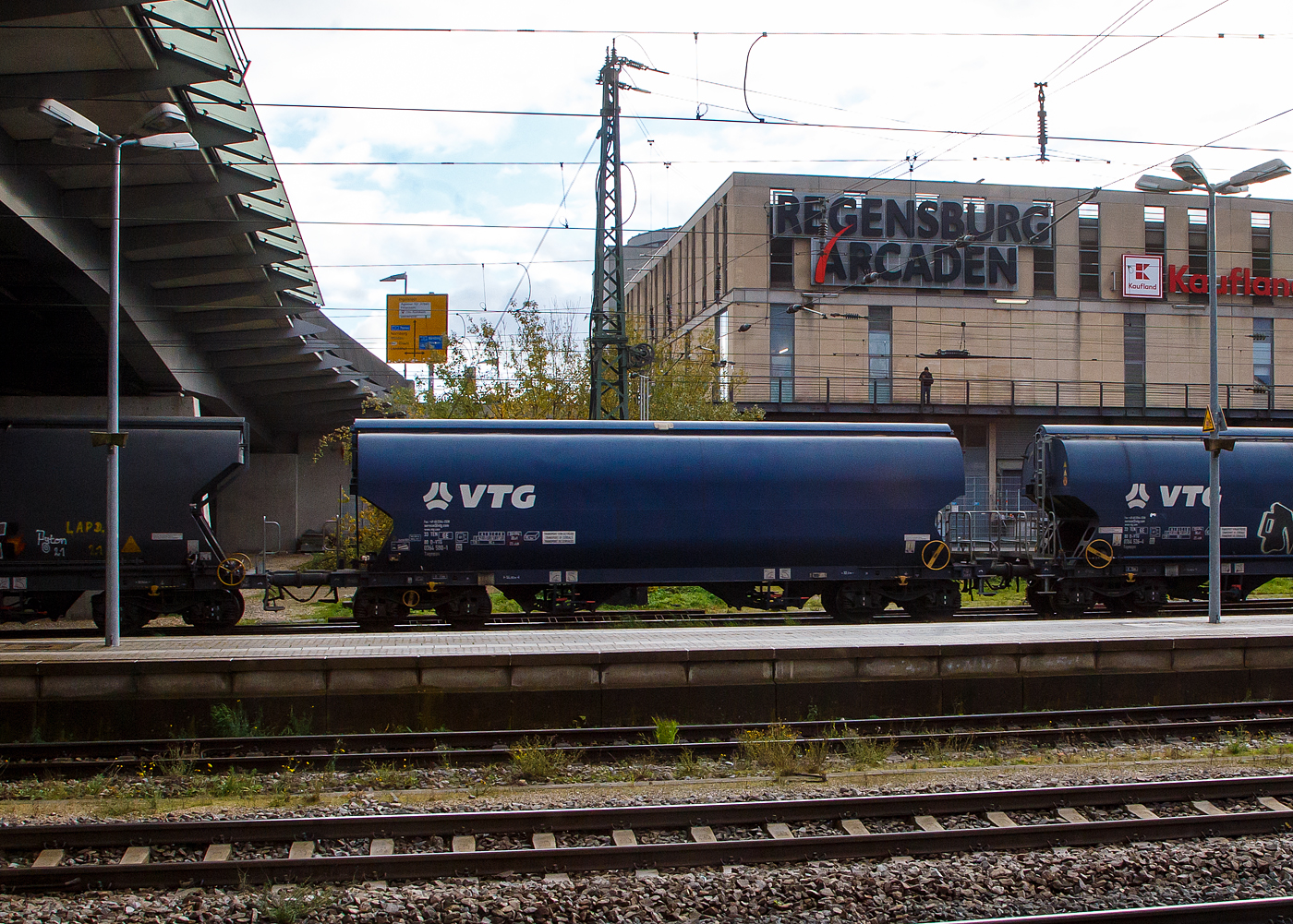 Vierachsiger Drehgestell-Schüttgutwagen mit Schwenkdach und dosierbarer Schwerkraftentladung für Getreide bzw. gedeckter 95 m³ Trichtermittenentladewagen, der Gattung Tagnpps, hier 33 80 0764 580 -1 D-VTG des Wagonvermieters VTG AG, am 24.11.2022 im Zugverband bei einer Zugdurchfahrt im Hauptbahnhof Regensburg.