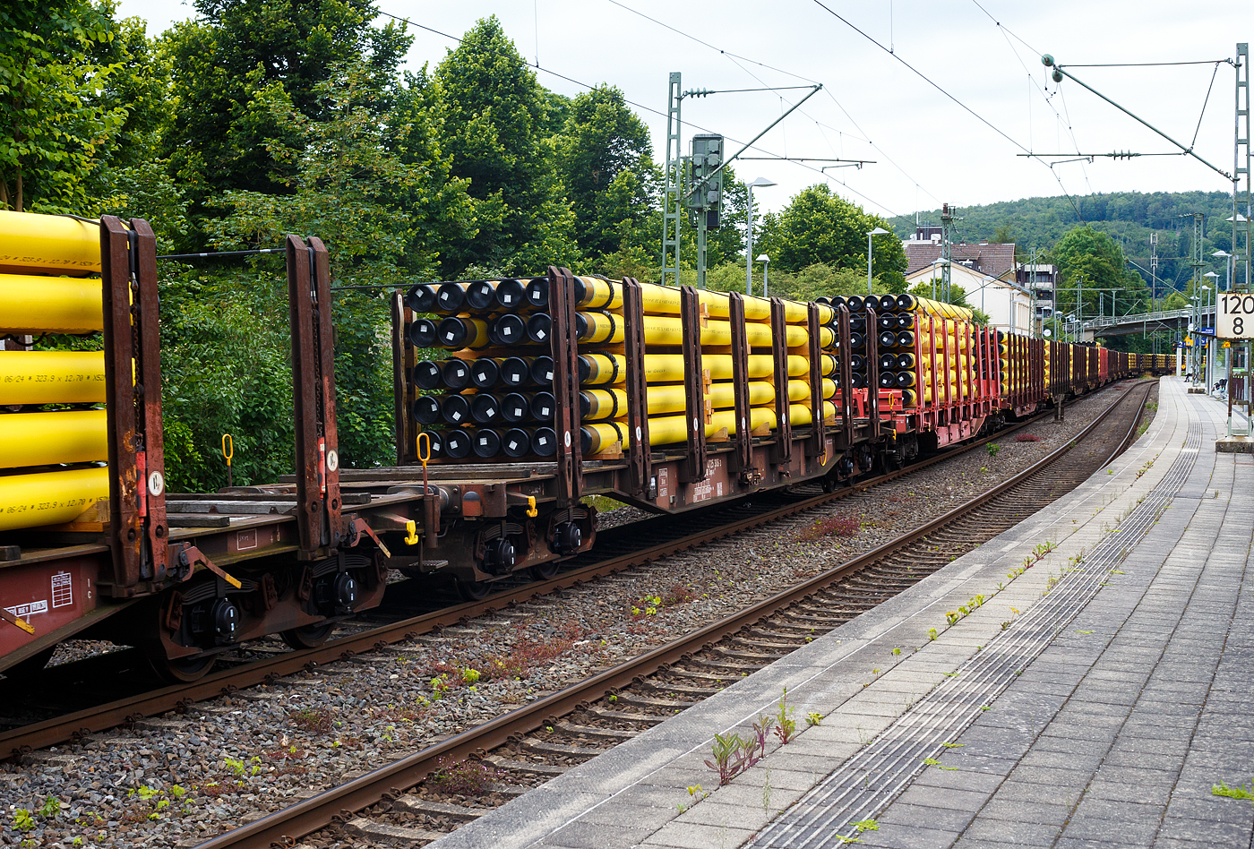 Vierachsiger Drehgestellflachwagen mit Rungen und Niederbindeeinrichtung, 31 80 4725 306-3 D-DB, der Gattung Snps-x 719.1, der DB Cargo AG am 20 Juni 2024 im Zugverband bei einer Zugdurchfahrt im Bahnhof Kirchen (Sieg). Hier beladen mit 30 gelb beschichteten Gasrohren bzw. HFI-längsnahtgeschweißte Stahlrohre Ø 323.9 x 12,7 (DN/NW 300 mm bzw. 12 ¾ Inch) mit gelber MAPEC® Polyethylen (HDPE)-Umhüllung), in Herstellungslänge vom 12 m. Das Metergewicht der Rohre beträgt 97,5 kg/m (ohne Umhüllung), so ist der Wagen mit ca. 36 t beladen. Der Hersteller der Stahlrohre ist die Salzgitter Mannesmann Line Pipe GmbH in Siegen (ex RW Fuchs).

Der Drehgestell-Flachwagen wurde speziell für den Transport von Rohren, Profilstahl, Flachstahlprodukten, sowie Stamm- und Schnittholz entwickelt und zeichnet sich durch hohe Ladekapazität aus. Das Ladegut wird bei der BA 719.1 durch Rungen mit Kunststoffleisten geschont, bei der für Holz vorgesehenen BA 179.0 sind keine Schonleisten montiert. Die Längsseiten sind jeweils mit acht besonders breiten und belastbaren Doppelrungen ausgerüstet, die mit dem Untergestell fest verbunden sind. Zur Verzurrung des Ladegutes ist jedes Rungenpaar mit einer Niederbindeeinrichtung versehen, die von einer Person bedient werden kann. Für die Auflage des Ladegutes sind hölzerne Ladeschwellen im Rungenbereich und im Abstand von 1 m von Wagenende vorhanden. Außerdem sind feste 5 mm niedrigere Hilfsladeschwellen zwischen den Rungen zur Unterstützung von leicht durchhängendem Ladegut (z. B. Schnittholz) angeordnet. Die Ladeschwellen sind genügend hoch, so dass die handelsüblichen Umschlagmittel verwendet werden können. Der Wagenboden ist mit einem begehbaren Loch- bzw. Riffelblech vollständig abgedeckt. Zur Aufnahme von Lasten oder zum Befahren mit Flurförderfahrzeugen sind die Abdeckungen nicht geeignet.

TECHNISCHE DATEN:
Gattung: Snps-x 719.1
Spurweite: 1.435 mm (Normalspur)
Länge über Puffer: 20.840 mm
Drehzapfenabstand: 15.800 mm
Radsatzstand in den Drehgestellen: 1.800 mm
Ladelänge: 19.600 mm
Ladebreite: 2.723 mm (zwischen den Rungen)
Fußbodenhöhe über SO: 1.280 mm (OK Ladeschwelle)
Rungenhöhe: 2.000 mm
Eigengewicht: 24.990 kg
Zuladung bei Lastgrenze S: 63,0 t (ab Streckenklasse D) ); DB Netz CM 57,0 t
Max. Geschwindigkeit: 100 km/h / 120 km/h (leer)
Kleinster Gleisbogenhalbmesser: 35 m
Bauart der Bremse: KE-GP
Verwendungsfähigkeit: RIV
