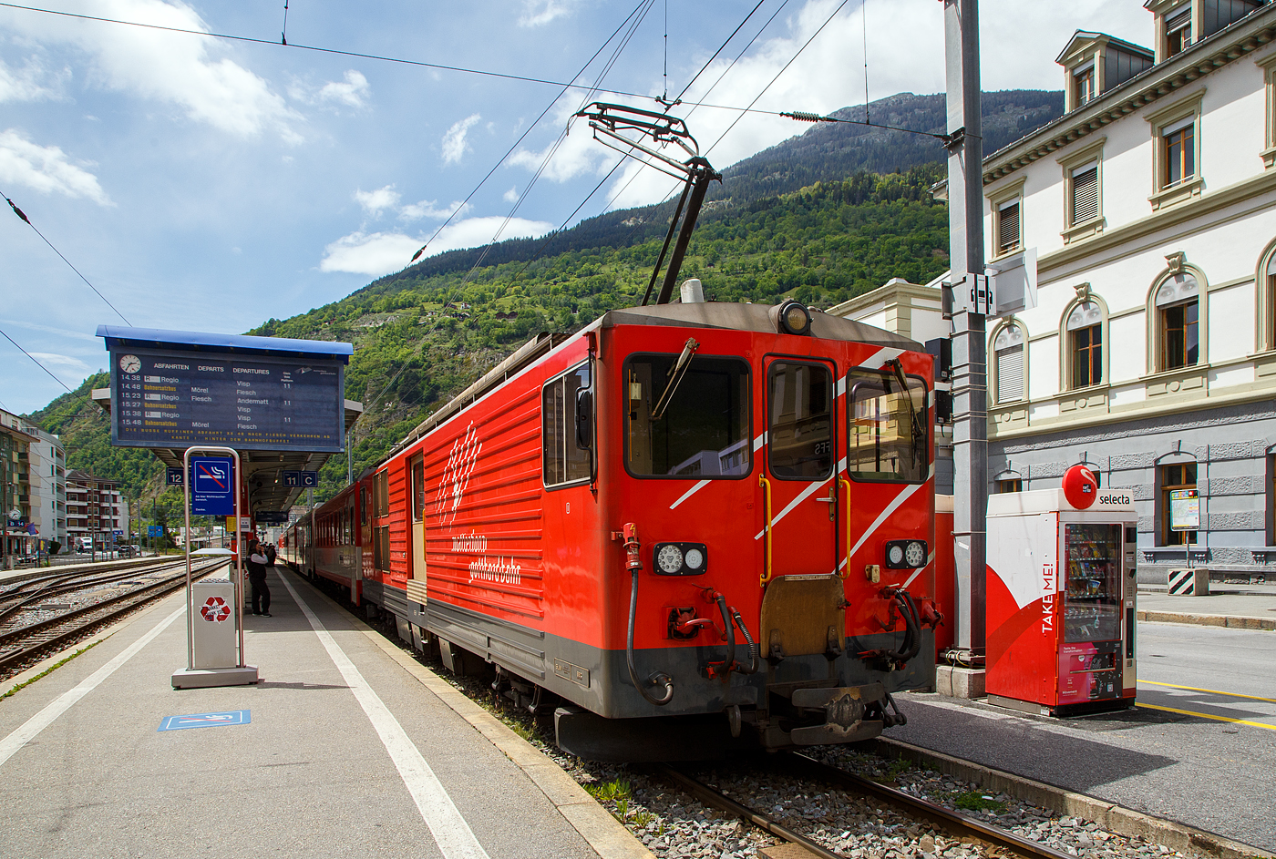 Von dem Gepäcktriebwagen Deh 4/4 II - 96  Münster   der Matterhorn-Gotthard-Bahn (MGB), ex FO 96  Münster   (Furka-Oberalp-Bahn), geschoben erreicht am 25.05.2023 der Regionalzug von Andermatt nach Visp den Bahnhof (Vorplatz) Brig.

Der Gepäcktriebwagen wurde 1984 von SLM (mechanischer Teil, Lokomotivkasten) und BBC (elektrische Ausrüstung) gebaut.