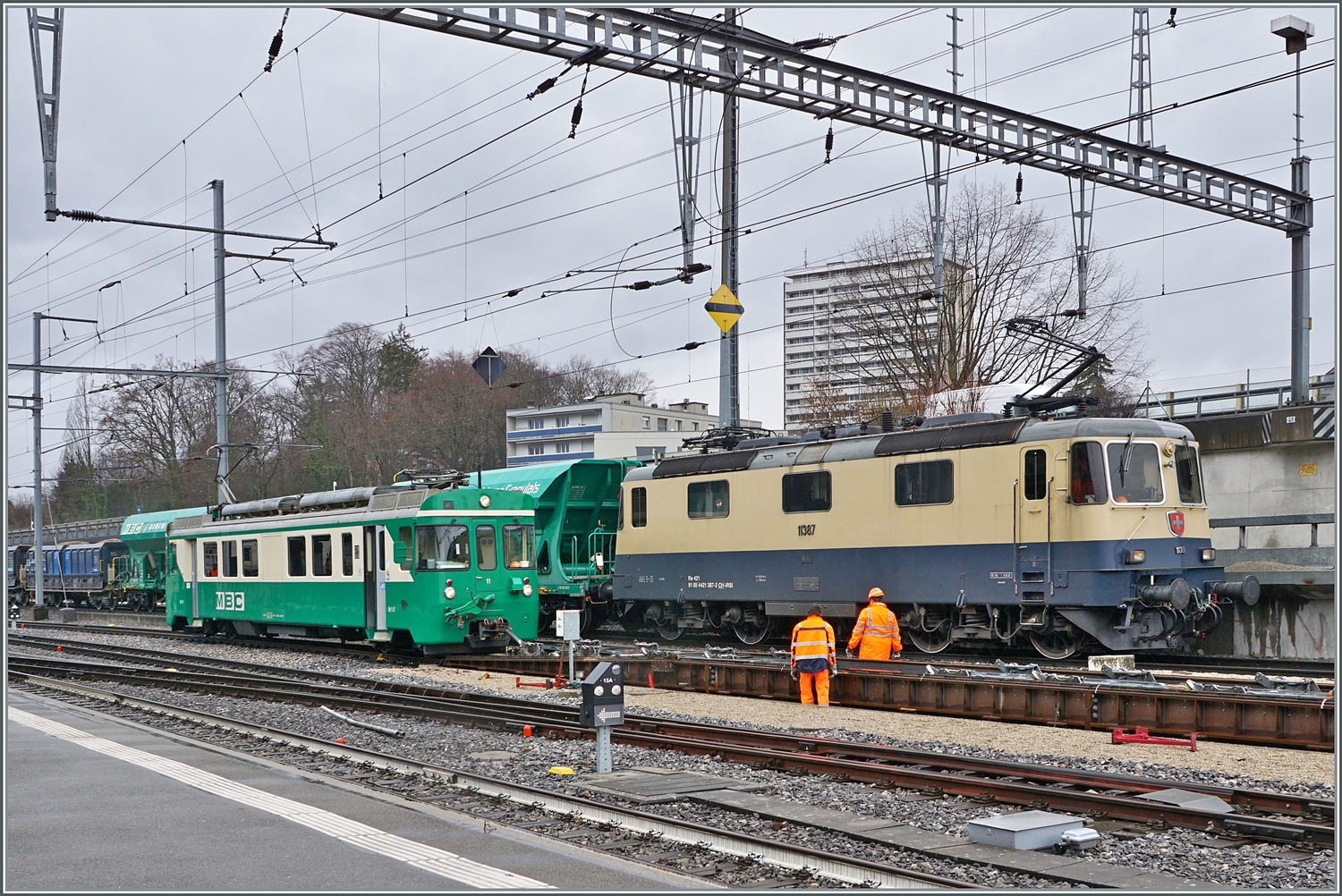 Während die IRSI/IGE  Rheingold  Re 4/4 II 11387 (Re 421 387-2) in Morges ihren Kieszug über die Rollbockgrube schiebt, rangiert der BAM MBC Be 4/4 11 Rollböcke.

22. Feb. 2024