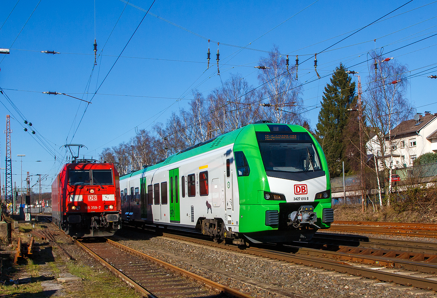 Während links auf dem Stumpfgleis die 185 359-7 der DB Cargo AG wartet, rauscht rechts der für die DB Regio AG – NRW fahrende dreiteilige Stadler FLIRT 3 XL 3427 015 (94 80 3427 015-7 D-STAP /  94 80 3827 015-3 D-STAP / 94 80 3427 515-6 D-STAP) der ZV VRR Eigenbetrieb Fahrzeuge und Infrastruktur, als RE 34 „Dortmund-Siegerland-Express“ (Dortmund - Letmathe - Siegen), von Kreuztal weiter in Richtung Siegen.

Der Stadler FLIRT 3 XL wurde 2020 von der Stadler Pankow GmbH in Berlin unter den Fabriknummern 42359 bis 42361 gebaut und an den Zweckverband Verkehrsverbund Rhein-Ruhr Eigenbetrieb Fahrzeuge und Infrastruktur geliefert. Eigentlich war dieser FLIRT 3 XL wie 9 weitere für die Bedienung der Regiobahnstrecke S 28 Kaarst - Neuss - Düsseldorf - Mettmann - Wuppertal vorgesehen, wo die Elektrifizierung bis 2020 erfolgen sollte. Da aufgrund von Verzögerungen der elektrische Betrieb voraussichtlich erst 2026 aufgenommen werden kann, wurden die inzwischen gelieferten Triebwagen u. a. von der DB Regio AG NRW eingesetzt.