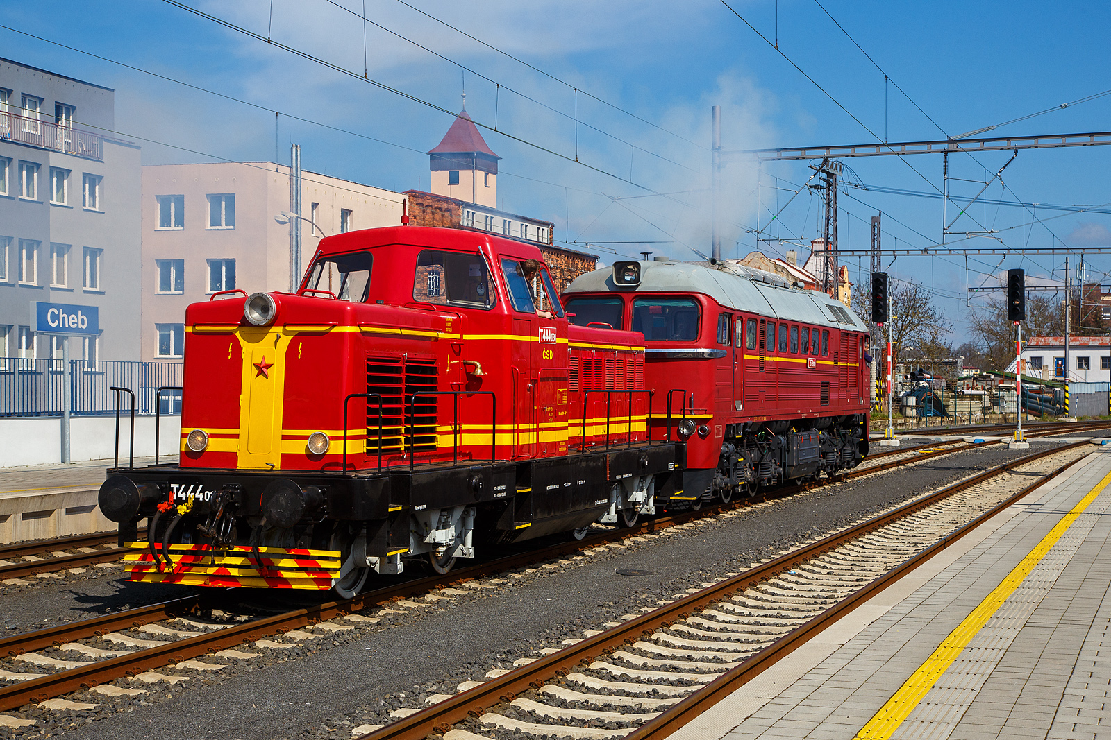 Wie in „alten Zeiten“ der ČSD in der Tschechoslowakei.....
Im Bahnhof Cheb (Eger) rangiert am 21.04.2023, die ex ČSD T679.1600 „Don Cicío“, heutige ČD 781 600-2 (CZ-ČD 90 54 3 781 600-2) mit dem Rotkäppchen („Karkulka“) T 444.030 (heute CZ- ČD 90 54 3 725 030-1) am Haken. Die Dieselabgaswolke kann man am Bild ja sehen, leider nicht den Sound.

Die T 444.030: 
Das Rotkäppchen („Karkulka“) T 444.030 (heute CZ- ČD 90 54 3 725 030-1) wurde 1963 von der Lokfabrik Turčianska strojarne n. p. Martin unter der Fabriknummer  40-00028 gebaut.

Die Baureihe T 444.0 (ab 1988 Baureihe 725) ist/war eine der wenigen dieselhydraulischen Lokomotiven der Tschechoslowakischen Staatsbahn ČSD. Sie wurde entwickelt, um auf Nebenbahnen und im Rangierdienst den Dampfbetrieb zu ersetzen. Die ersten zwei Prototypen wurden 1959 von ČKD in Prag geliefert. Die Serienfertigung erfolgte bei Turčianske strojarne n. p. Martin in der heutigen Slowakei. Insgesamt wurden für die ČSD 113 und für Industriebetriebe 61 Maschinen gebaut und ausgeliefert.

Die wegen des roten Anstriches „Karkulka“ (Rotkäppchen) genannten Lokomotiven besaßen einen Reduktionswandler für den Strecken- und Rangierdienst. Aus Ihnen wurden die spätere Baureihe T 444.1 mit einem Dampfkessel für die Wagenheizung abgeleitet. Dadurch wurde die Brennstoffreserve bei der BR T 444.1 von 4000 l auf 1500 l verkleinert. Die T 444.0 wurden 1988 in die Baureihe 725 umgezeichnet. Da die Lokomotiven keinen Dampfkessel besaßen und der Güterverkehr auf Nebenbahnen kontinuierlich zurückging, konnte bis 1992 auf ihre Dienste verzichtet werden. Etliche Maschinen sind jedoch fahrfähig erhalten geblieben

TECHNISCHE DATEN:
Gebaute Anzahl: 174
Hersteller: ČKD (Entwicklung und Prototypen), Turčianska strojarne n. p. Martin
Baujahre:  1959–1965
Spurweite: 1.435 mm
Achsformel: B´ B´ 
Länge über Puffer: 12.640 mm
Dienstgewicht: 56 t
Treibraddurchmesser:  1.000 mm
Motor: V-12-Zylinder-Viertakt-Dieselmotor vom Typ ČKD K 12 V 170 DR
Motorleistung: 534 kW (726 PS), Nenndrehzahl 1400 U/min
Höchstgeschwindigkeit: 70 km/h Streckengang / 35 km/h Rangiergang
Anfahrzugkraft: 158 kN
Leistungsübertragung: hydrodynamisch