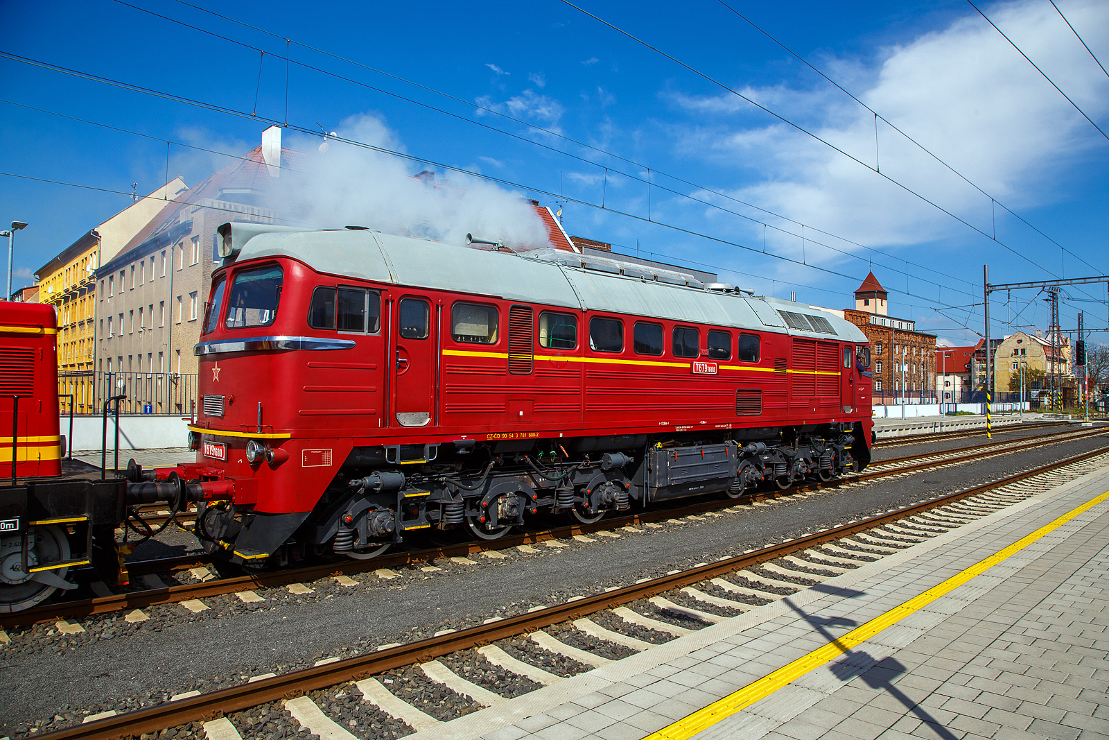Wie in „alten Zeiten“ der ČSD in der Tschechoslowakei.....
Im Bahnhof Cheb (Eger) rangiert am 21.04.2023, die ex ČSD T679.1600 „Don Cicío“, heutige ČD 781 600-2 (CZ-ČD 90 54 3 781 600-2) mit dem Rotkäppchen („Karkulka“) T 444.030 (heute CZ- ČD 90 54 3 725 030-1) am Haken. Die Dieselabgaswolke kann man am Bild ja sehen, leider nicht den Sound.

Lokomotive der wurde 1979 von der Lokomotivfabrik Luhansk, deutsche Transliteration Luhanskyj Teplowosobudiwnyj Sawod (LTS), in der damaligenSowjetunion (heute Ukraine) unter der Fabriknummer 3426 gebaut. Die Herstellerbezeichnung ist LTS M62. Die für die DDR gebaute Variante (weitgehend baugleich mit dieser hier) der sowjetischen Bauart M62 sind in Deutschland bekannt als DR V 200 „Taigatrommel“, später DR 120, zuletzt DB 220.

Die ČSD-Baureihe T 679.1 (ab 1988 Baureihe 781) sind dieselelektrische Lokomotiven der ehemaligen Tschechoslowakischen Staatsbahn (ČSD) für den schweren Güterzugdienst. Wegen ihrer Herkunft erhielten die Lokomotiven den Beinamen Sergej. 

Die Lokomotiven wurden ab Mitte der 60er Jahre in der sowjetischen Lokomotivfabrik Woroschilowgrad (später Luhansk) für den Einsatz bei den Bahnverwaltungen des gesamten RGW entwickelt und produziert. Nachdem bereits die Ungarische Staatsbahn (MÁV) und die Polnischen Staatsbahnen (PKP) Lokomotiven dieses Typs beschafft hatten, entschied sich Mitte der 60er Jahre auch die ČSD für solche Lokomotiven.

1966 wurden die ersten 50 Lokomotiven an die ČSD geliefert. Bis 1979 beschaffte die ČSD insgesamt 599 Lokomotiven dieser Baureihe. 25 Lokomotiven der ersten Serie wurden breitspurig als T 679.5 für die grenzüberschreitende Strecke Bahnstrecke Uschhorod–Haniska (Sowjetunion, heute Ukraine) in Dienst gestellt. Nach der Elektrifizierung ihrer Stammstrecke in den Jahren 1973 bis 1978 wurden sie dort nicht mehr benötigt. Ein Teil dieser Lokomotiven wurde darum auf Regelspur umgespurt. Acht Lokomotiven blieben jedoch für die Bedienung der Werksanschlüsse breitspurig und erhielten ab 1988 die neue Baureihenbezeichnung 781.8. Die breitspurigen Lokomotiven wurden 1991 ausgemustert und verschrottet. 

Bereits 1987 verringerte sich der Lokomotivbestand erstmals, als neun Lokomotiven an die Ungarische Staatsbahn MÁV verkauft wurden. Nach 1990 wurden die Lokomotiven durch den zurückgehenden Güterverkehr und die fortschreitende Elektrifizierung der wichtigsten Hauptstrecken zunehmend überflüssig. 1997 endete der Einsatz der Sergejs in der Slowakei. In Tschechien waren die Lokomotiven für den schweren Güterverkehr auf der sogenannten „Podkrušnohorska magistrála“ (Strecke Chomutov–Cheb) vorerst unverzichtbar. Letztes Einsatzgebiet der Lokomotiven in Tschechien waren die schweren Kohleganzzüge von Sokolov zum Kraftwerk Arzberg in Oberfranken. Diese Verkehre endeten am 30. November 2002 mit der Stilllegung des Kraftwerkes.

Konstruktion und Technik:
Die M62 ist als schwere sechsachsige Güterzuglokomotive konstruiert. Der Rahmen ist als selbsttragender Brückenrahmen aus zwei inneren Hauptlängsträgern aus Doppel-T-Trägern und zwei äußeren Längsträgern aus U-Profilen aufgebaut, die durch Deckbleche und die Zugkästen an den Frontseiten verbunden sind. Der Lokkasten ist aus gekanteten Profilen und gesickten Blechen geschweißt. Der Rahmen der dreiachsigen Drehgestelle besteht aus zwei äußeren Längs- und zwei inneren Querträgern und dem darüber angeordneten Drehzapfenträger. Der hierauf mit dem Drehzapfenlager aufgesetzte Lokkasten ist mit einer Abstützrückstelleinrichtung abgestützt.

Herzstück dieser Lok ist der Dieselmotor, ein wassergekühlter V 12 Zylinder- Zweitakt- mit zwei Abgasturboladern und Rootsgebläse mit einem Hubraum von 149,6 Litern  vom Typ Kolomna 14 D 40. Die mechanische Leistung beträgt 1.470 kW (1.998 PS) bei einer Drehzahl von 750 U/min. Die Leistung wurde durch einen fremderregten Gleichstromgenerator für die Fahrmotoren in Gleichstrom umgewandelt. Die Leistungsregelung erfolgte durch einen magnetischen Flussregler im Erregerfeld der Erregermaschine. Die Fahrmotoren sind Reihenschlussmotoren. Deren Traktionsleistung betrug zusammen 1,270 kW (1727 PS). Um Ankerströme und Drehmoment der Fahrmotoren im oberen Geschwindigkeitsbereich wieder anzuheben, besaß die Lok zwei Shuntierungsstufen, die parallel zu den Erregerwicklungen der sechs Tatzlager-Fahrmotoren geschaltet wurden. Eine ähnliche Konstruktion verwendet die Lokfamilie der DR-Baureihe 130. Entsprechend der Auslegung als Güterzuglokomotive besitzt die M62 keine Zugheizeinrichtung. Einsätze im Reisezugdienst waren daher auf wärmere Jahreszeiten beschränkt oder erforderten den Einsatz von Heizwagen bzw. von Wagen mit Eigenheizung.

Ein besonderes Bauteil ist das Rootsgebläse, es fördert Verbrennungsluft und erzeugt eine Vorverdichtung von 0,2 bar. Das ist notwendig, weil ein Zweitakt-Motor durchgespült werden muss, er kann mit gleichzeitig offenen Einlassschlitzen und Auslassventilen nicht selbsttätig ansaugen. Nach dem Start laufen die beiden Turbolader hoch und steigern den Ladeluftdruck auf rund 1,2 bar. Der Dieselmotor hat eine Leerlaufdrehzahl von 400 U/min, aber schon bei 750 U/min seine Höchstdrehzahl. Der Motor besitzt Zylinder in V-Anordnung mit je 12,46 Litern Hubraum. Dabei sitzen die Kolben der B-Seite mit Anlenkpleueln auf den Hauptpleueln der A-Seite. Damit ändern sich die Kolbengeschwindigkeiten zwischen A- und B-Seite. Der Motor erzeugt auf beiden Zylinderbänken unterschiedlich viel Leistung. Der Kraftstoffvorrat beträgt 3.900 Liter Dieselöl.

Die Lüfter für Fahrmotoren und Traktionsgenerator sind mechanisch über Gelenkwellen vom Dieselmotor angetrieben. Der Kühlerlüfter wurde auch direkt vom Dieselmotor angetrieben, zur Steuerung ist eine Strömungskupplung dazwischengeschaltet.

Charakteristisches Merkmal der ersten Lieferserien der M62, die noch ohne Schalldämpfer geliefert wurde, war das laute Auspuffgeräusch, das ihnen in der DDR zum Spitznamen „Taigatrommel“ verhalf.  In Deutschland, Tschechien und der Slowakei sind die M62 aus dem Dienst der Staatsbahnen ausgeschieden, in allen anderen Ländern sind sie noch im Einsatz. 

TECHNISCHE DATEN:
Gebaute Anzahl: 574  Stück T 679.1 und 25 Stück T 679.5 (Breitspur)
Hersteller:  Lokomotivfabrik Lugansk
Baujahre: 1966 bis 1979
Achsformel: Co’Co’
Spurweite:  1.435 mm (1.520 mm bei T 679.5)
Länge über Puffer: 17.550 mm
Höhe: 4.493 mm
Breite: 2.950 mm
Drehzapfenabstand: 8.600 mm
Achsabstand im Drehgestell: 4.200 mm (2 x 2.100 mm)
Treibraddurchmesser:  1.050 mm
Kleinster bef. Halbmesser: 125 m
Dienstgewicht: 116 t 
Höchstgeschwindigkeit: 100 km/h
Installierte Leistung: 1.471 kW (1.998 PS)
Traktionsleistung (Leistung am Rad): 1.271 kW (1.727 PS)
Anfahrzugkraft: 260 kN
Dauerzugkraft: 200 kN
Motorentyp: Kolomna 14 D 40
Motorbauart: Zweitakt-Zwölfzylinder-V-Motor
Nenndrehzahl: 750 U/min (Leerlauf 400 U/min)
Leistungsübertragung: elektrisch
Anzahl der Fahrmotoren: 6 vom Typ ED 107
Tankinhalt: 3.900 l
Bremse: ŠKODA N-O, Dako-BS-2

Quellen: Wikipedia, atlaslokomotiv.net