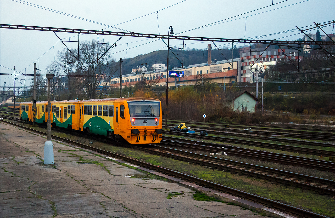 Wir überholen zwei gekuppelte Regionova (814 111/ 914 111 und 914 125/814 125) der České dráhy (ČD) am 24.11.2022 bei Praha-Smichov. Aufnahme aus dem Zugheraus.

Die Fahrzeuge der ČD-Baureihe 814/914 entstanden im Rahmen eines Rekonstruktionsprogrammes (2005 bis 2012) aus den Fahrzeugen der ČD-Baureihe 810,ex ČSD M 152.0  Chcípák  (Brotbüchse). Von den ČD werden sie als „Regionova“ vermarktet.