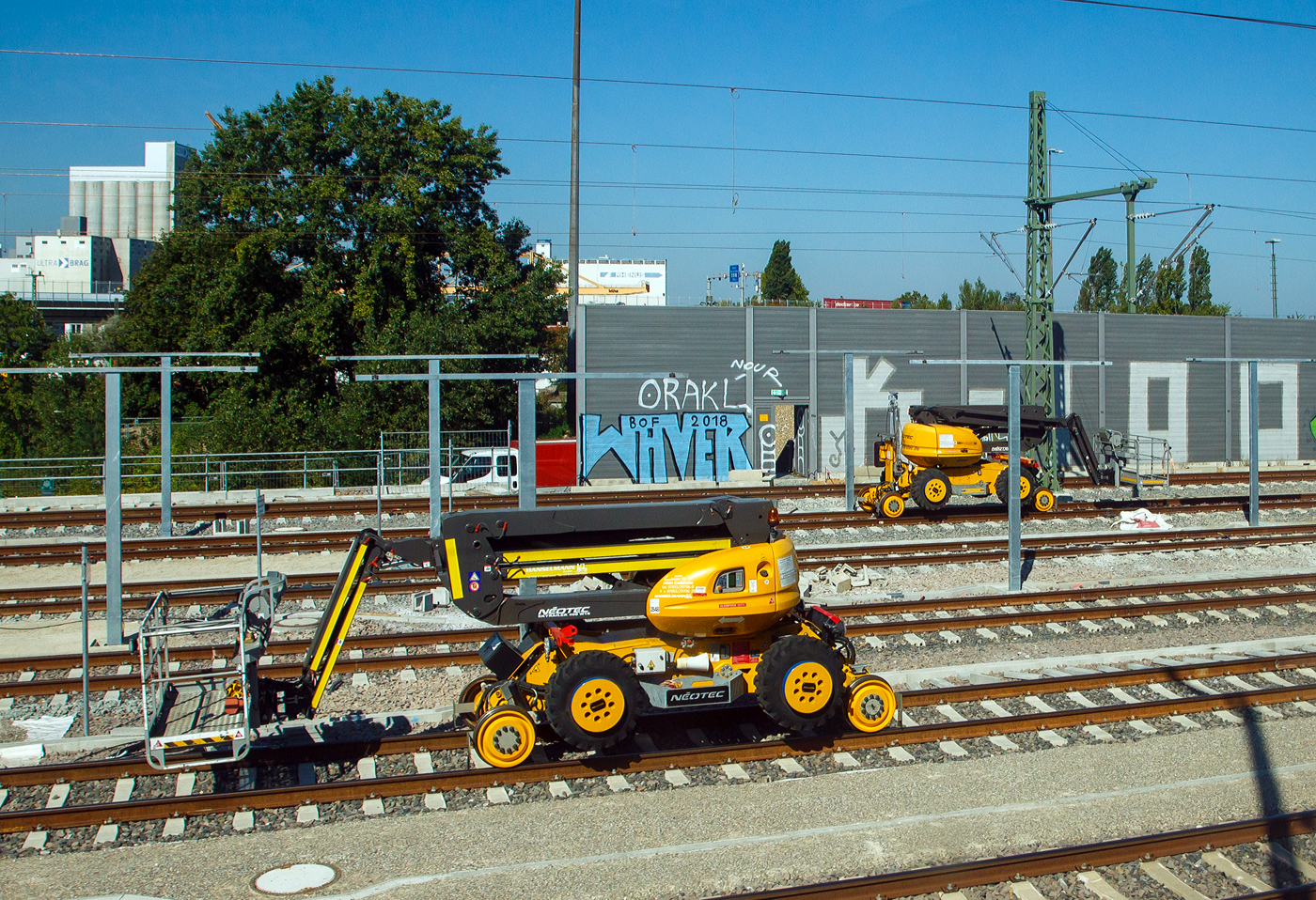 Zwei ZW-Hubarbeitsbühnen für die Oberleitungsmontage stehen am 07.09.2023 bei der Bahnbaustelle zwischen Basel und Weil am Rhein (Bild aus einem ICE heraus).

Diese ZW-Hubarbeitsbühnen vom Händler und Vermieter Hanselmann GmbH aus Crailsheim sind Spezial Arbeitsbühne vom Typ NÉOTEC SKYRAILER 400W16 des Herstellers Manitou. Die Maschinen sind für das DB-Schienennetz zugelassen. 

Manitou NEOTEC SKYRAILER 400RR für den Einsatz auf einem Gleisstrang oder auch schwere Gelände Zwei-Wege-Arbeitsbühne (Straße-Schiene) Korbdrehung 2x90° - 4-Rad Antrieb - 2 Lenkachsen - Steigfähigkeit 25% - Rückfahrkamera - maximale Gleisüberhöhung 200 mm - Bahnräder/Schienenrad-Durchmesser 580 mm - Profil Bahnräder UIC - Stromkreislauf: 12V - 105A

TECHNISCHE DATEN:
Spurweite (Schiene): 1.435 mm 
Achsabstand: 9.900 mm
Antriebsart: Diesel (Kubota V2403-M 45HP)
Tragkraft: 400 kg
Fahrgeschwindigkeit: Straße 6 km/h / Schienen16 km/h
Eigengewicht: 12.750 kg