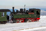 Die Jung-Malletlok 99 5902 der HSB, ex DR 099 111-7, ex DR 99 5902-4, ex NWE 14, ex NWE 12 (ab 1927) hat mit HSB-Traditionszug am 23.03.2013 den Brocken erreicht. Der Bahnhof Brocken (1.125 m ü.NN) ist der Kopfbahnhof am Gipfel des 1.142m hohen Brocken im Harz. Am 23.03.2013 herrschte hier ein eisiger Wind bei minus 17° Celsius.

Die Lok wurde 1898 von Arnold Jung Lokomotivfabrik in Jungenthal bei Kirchen a.d. Sieg unter der Fabriknummer 261 gebaut und an die NWE (Nordhausen-Wernigeroder Eisenbahn-Gesellschaft) als Nr. 14 geliefert ab 1927 wurde sie zur NWE 12.

Von den 12 Malletmaschinen der NWE (Nr. 11 bis 22) sind nur drei Maschinen übrig geblieben. Alle diese Maschinen, mit Ausnahme der NWE 12, 13 und 19 welche aus Güstrow stammten, waren 1897/98 und 1901 von der Firma Jung geliefert worden. Die Güstrower Maschinen sowie die NWE 12, 13 und 19 wurden im ersten Weltkrieg an die Heeresfeldbahnen nach Frankreich abgegeben. Die NWE 20 später 12, ist 1927 im Thumkuhlental verunglückt und wurde verschrottet.

Die Kessel der Maschinen lagen bei der Auslieferung vom Werk etwas niedriger auf dem Rahmen als heute. Ab 1920 wurden die Kessel etwas anders montiert.

Die Malletmaschinen wurden seit den 50er Jahren vorrangig im Selketal eingesetzt. Der Grund ist ihre gute Kurvenläufigkeit. Außerdem hatte sich dort die Verfügbarkeit an Loks nach dem Einsatz der ersten Neubaulokomotiven grundlegend gebessert, sodass es möglich war, die Mallets abzugeben. Zusammen mit der 99 6001 meisterten sie den gesamten Verkehr im Selketal bis Mitte der 80er Jahre.

Ende der 80er wurden die Mallets  Z‑gestellt  weil sie die inzwischen auf Druckluftbremse umgestellten Züge nicht mehr befördern konnten - denn die Mallets hatten von Haus aus keine Druckluftanlage. Die Neubaulokomotiven fuhren nun im Selketal.

Um die Mallets mit einer Druckluftanlage auszurüsten, wurden verschiedene Lösungsvarianten in Erwägung gezogen. So zum Beispiel die Möglichkeit, einen Kreiselkompressor mit Hilfe eines Dampfturbos, wie der der Lichtmaschine, anzutreiben. Man kam aber wieder auf die Ausrüstung mit einer Luftpumpe zurück. Diese wurde in einem Teil des Wasserkastens untergebracht um das gesamte Erscheinungsbild der Maschinen nicht grundlegend zu verändern.

Die Lokomotiven 99 5901 und 99 5902 sind als älteste betriebsfähige Malletdampflokomotiven in Deutschland im Sonderreisezugverkehr im Einsatz. Die 99 5903 ist von der Instandsetzung zurückgestellt und wird für besondere Veranstaltungen durch die HSB weiter genutzt..

Technische Daten dieser Loks:
Hersteller: Arnold Jung Lokomotivfabrik in Jungenthal bei Kirchen a.d. Sieg

Baujahr: 1898
Achsfolge: B'B
Gattung: K44. 9
Spurweite: 1.000 mm (Meterspur)
Länge über Puffer: 8.875 mm
Drehgestellachsstand: 1.400 mm
Gesamtradstand: 4.600 mm
Kesselüberdruck : 14 bar
Zylinderanzahl: 4
ND-Zylinderdurchmesser: 425 mm
HD-Zylinderdurchmesser: 285 mm
Kolbenhub: 500 mm
Zylinderdruck: Hochdruck 14 bar, Niederdruck 5 bar, mit Anfahrventil max 7 bar
Leistung: 255 PSi (190 kW)
Höchstgeschwindigkeit: 30 km/h (Vor- und Rückwärts)
Dienstgewicht: 33,7 t
Kohlevorrat: 2,5 t
Wasservorrat: 5 m³
Achslast: 8,5 t