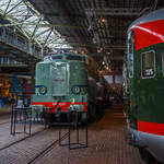 Die Elektrolokomotive NS 1201 der NS-Baureihe 1200 am 24 Juni 2025 im Het Spoorwegmuseum (bis 2005 NSM - Nederlands Spoorwegmuseum / Niederländischen Eisenbahnmuseum) in Utrecht im ehemaligen Bahnhof Maliebaan. Ein Eisenbahnmuseum das zum Verweilen einlädt.

Die Lok wurde 1951 von Werkspoor in Utrecht unter der Fabriknummer 928 gebaut (Baldwin-Lizenz) und an die NS - Nederlandse Spoorwegen (Niederländischen Staatsbahnen, heute Niederländische Eisenbahnen AG) geliefert. Wobei die Entwicklung und Konstruktion, sowie auch einige Teile, von Baldwin Locomotive Works in Philadelphia (USA) stammt. Auch die Entwicklung der Elektrotechnik stammt aus den Vereinigten Staaten und zwar von Westinghouse Electric Corporation (Monroeville), diese wurde von Heemaf in Hengelo (Westinghouse-Lizenz) geliefert.

Die Baureihe 1200 der Niederländischen Eisenbahnen (NS) ist eine sechsachsige Elektrolokomotivbaureihe aus den Jahren 1951 bis 1953. Die Lokomotiven waren bis 1998 bei der NS im Einsatz.

Die Nase war der erste Teil dieser unglaublich starken und robusten Lokomotive, der ins Auge fiel. Sie sollte dem Lokführer bei Kollisionen einen besseren Schutz bieten. Diese Lokomotiven wurden in den Niederlanden nach einem amerikanischen Design und mit einigen amerikanischen Teilen gebaut, die teilweise durch amerikanische Dollar über den Marshall-Plan finanziert wurden. Die NS nutzte diese Lokomotiven, um sowohl Personenzüge als auch Güterzüge zu ziehen. Ihre wichtigste Aufgabe war es Schnellzüge zu ziehen. Als sich die NS 1995 trennte, wurden alle 1200er Jahre an NS Cargo übertragen und begannen im Güterverkehr zu arbeiten. 

Nach Ende des Zweiten Weltkrieges gab es großen Fahrzeugmangel bei der NS. Da man keine Erfahrungen mit dem Bau elektrischer Lokomotiven hatte, kaufte man Lokomotiven bei verschiedenen Lieferanten. Die bei Baldwin konstruierten Lokomotiven wurden bei Werkspoor in Utrecht gefertigt. Die bei Westinghouse entwickelte Elektrotechnik wurde von Heemaf in Hengelo geliefert. Von den ursprünglich 75 georderten Lokomotiven wurden nur 25 ausgeliefert. Der amerikanische Einfluss ist an den hochliegenden Führerständen und den großen, dem Schutz des Lokführers dienenden Vorbauten erkennbar. Am 30. November 1950 wurden 25 Loks bestellt, am 27. September 1951 konnte die erste Probefahrt stattfinden. Am 9. Februar 1952 wurde die 1201 offiziell in Dienst gestellt, der Preis pro Lok betrug 765.000 NFL (ca. 347.000 Euro).

Die Loks hatten sechs Motoren des Typs TM94. Die ersten 14 Lokomotiven waren türkis lackiert, danach setzte sich wegen des sichtbaren Abriebs der Stromabnehmer eine rotbraune Farbgebung durch. Ab 1954 erhielten alle Loks eine blaue Farbgebung, 1971 erhielt die erste Lok die neuen NS-Hausfarben grau/gelb, 1983 war auch die letzte Lok entsprechend umlackiert. Am 30. März 1998 endete der planmäßige Einsatz bei der NS.

Fünf weitere Lokomotiven (1214, 1215, 1218, 1221, 1225) wurden 1999 an die ACTS Nederland BV verkauft. Diese vermietete 2010 drei Lokomotiven (1214, 1215, 1225) an die Eisenbahngesellschaft Euro-Express Treincharter (EETC). Von der wurden sie bis April 2015 unter anderem vor den Nachtzügen Niederlande–Österreich zwischen Amsterdam und Venlo eingesetzt. Fünf Maschinen (1201, 1202, 1211, 1218, 1221) sind als Museumslokomotiven erhalten. NS 1211 ist Botschafterlok im Bahnpark Augsburg. Leihgeber ist das Eisenbahnmuseum Utrecht.

TECHNISCHE DATEN:
Hersteller mech.: Werkspoor (in Lizenz von Baldwin)
Hersteller Elektrik: Heemaf (in Lizenz von Westinghouse)
Baujahre: 1950 bis 1953
Ausmusterung bei NS: bis 1998 
Gebaute Anzahl: 25
Nummerierung: NS 1201 bis 1225
Spurweite: 1.435 mm (Normalspur)
Achsfolge: Co’Co’ 
Länge über Puffer: 18.086 mm
Höhe: 4.064 mm
Treibraddurchmesser: 1.100 mm (neu)
Dienstgewicht: 108 t
Antriebsmotoren: 6 Stück Heemaf vom Typ TM 94
Getriebeübersetzung: 20 : 71
Höchstgeschwindigkeit: 130 km/h (Planmäßig) / 150 km/h (technisch möglich)
Stundenleistung: 6 x 392 kW = 2.350 kW
Dauerleistung: 6 x 367 kW = 2.200 kW
Anfahrzugkraft: 195 kN
Dauerzugkraft: 164 kN bei 80 km/h / 64,7 kN bei 123 km/h
Stromsystem: 1,5 kV DC (=)
Kleister befahrbarer Gleisbogen: R 100 m