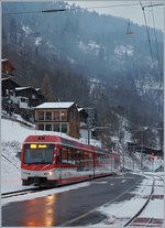 Der MGB ABDeh 4/8 2026 wartet in seinem Zugsausgangsbahnhof Fiesch auf die Abfahrt nach Zermatt, w�hrend im Hintergrund, schlecht sichtbar, eine Seilbahn aus Eggishorn schwebt.